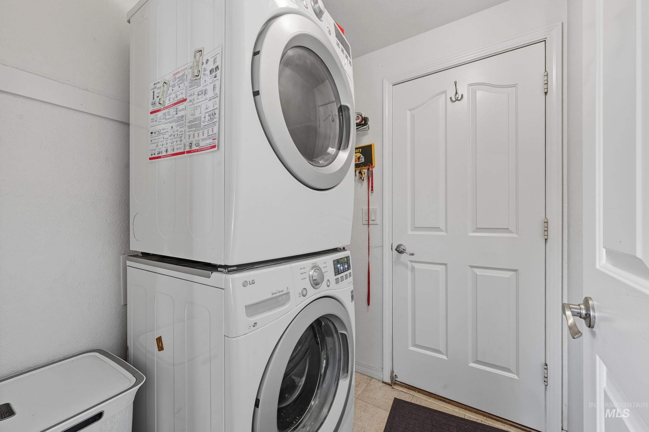 Laundry room featuring estacked washer and dryer and light tile patterned floors