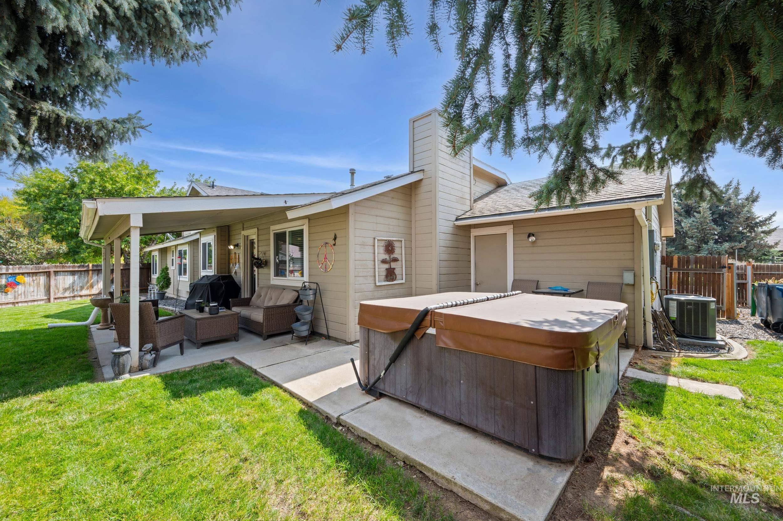Rear view of property with a hot tub, a patio area, an outdoor living space, a chimney, and a shingled roof