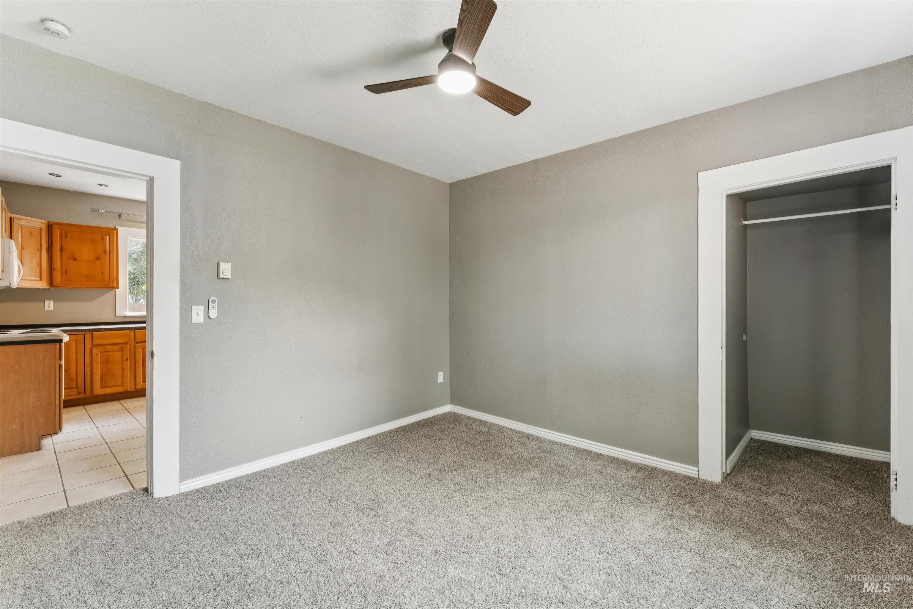 Unfurnished bedroom featuring light colored carpet, a ceiling fan, light tile patterned floors, and a closet