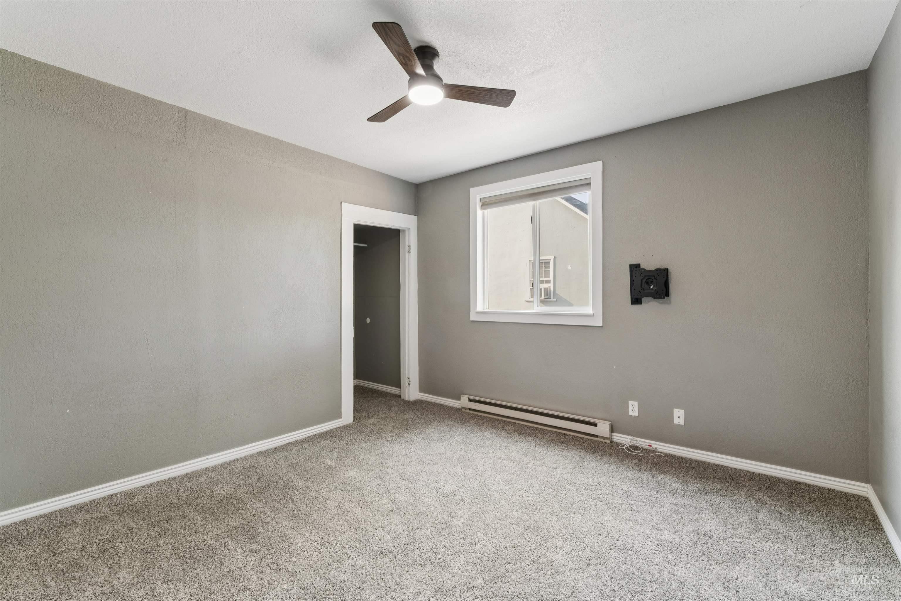 Spare room featuring baseboard heating, carpet, and ceiling fan