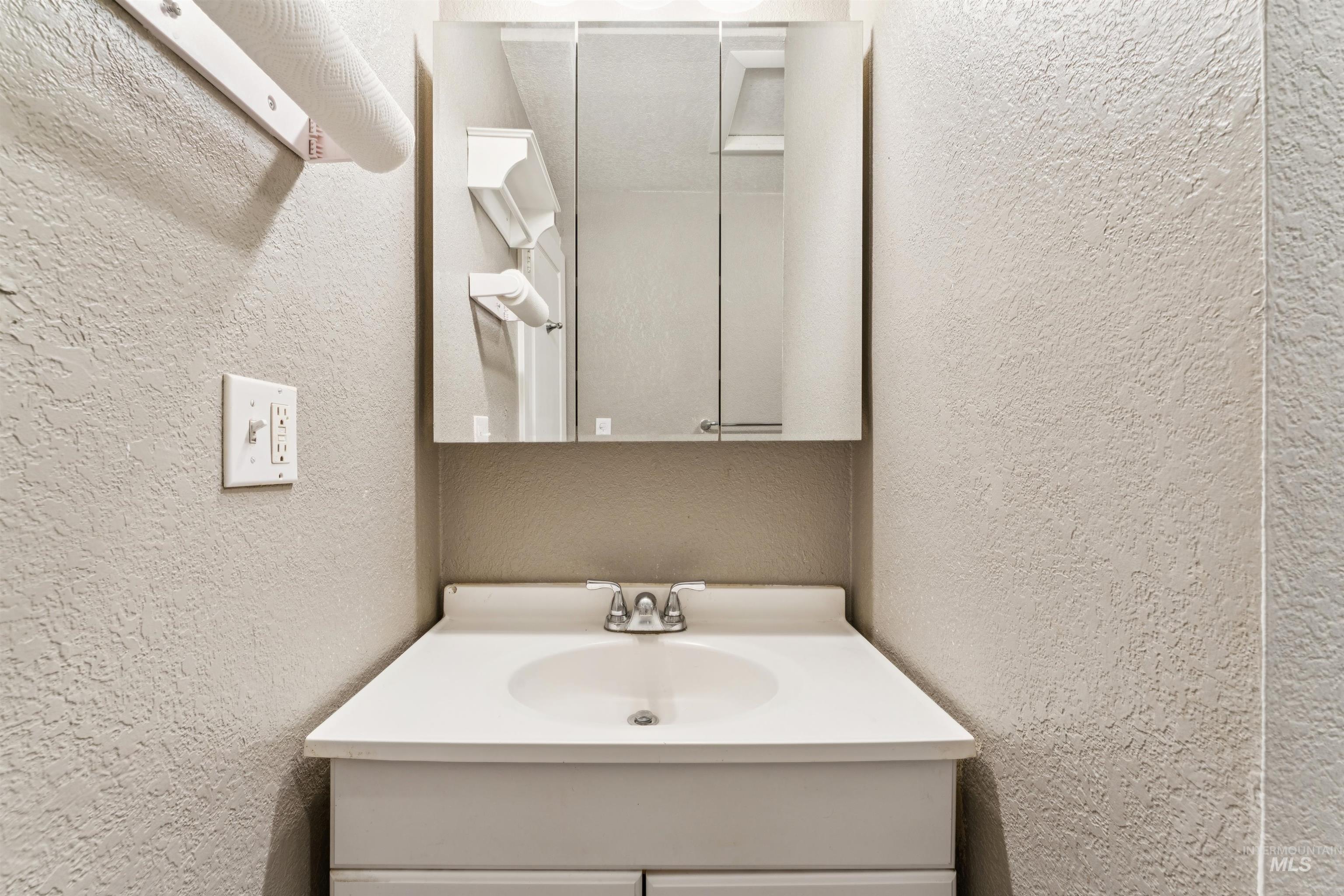Bathroom with vanity and a textured wall