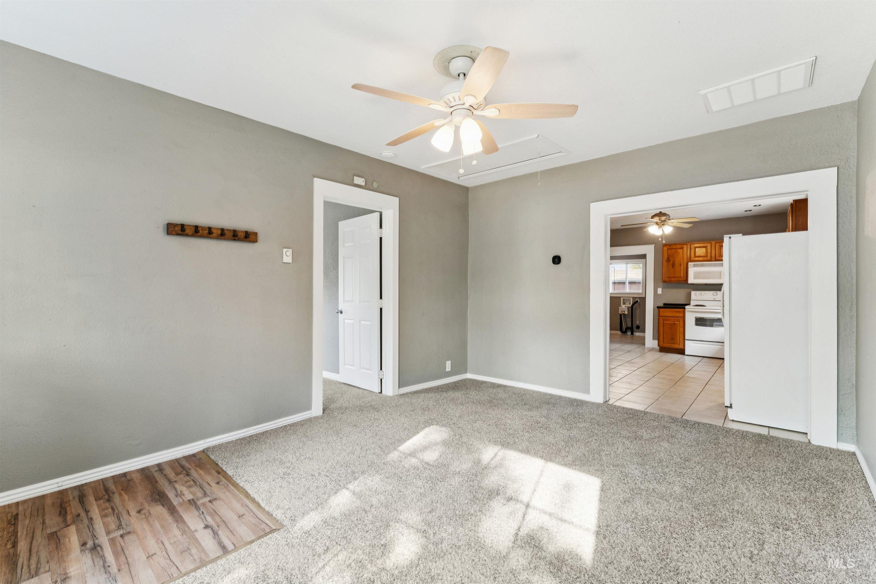 Unfurnished room with ceiling fan, attic access, light colored carpet, and light tile patterned floors