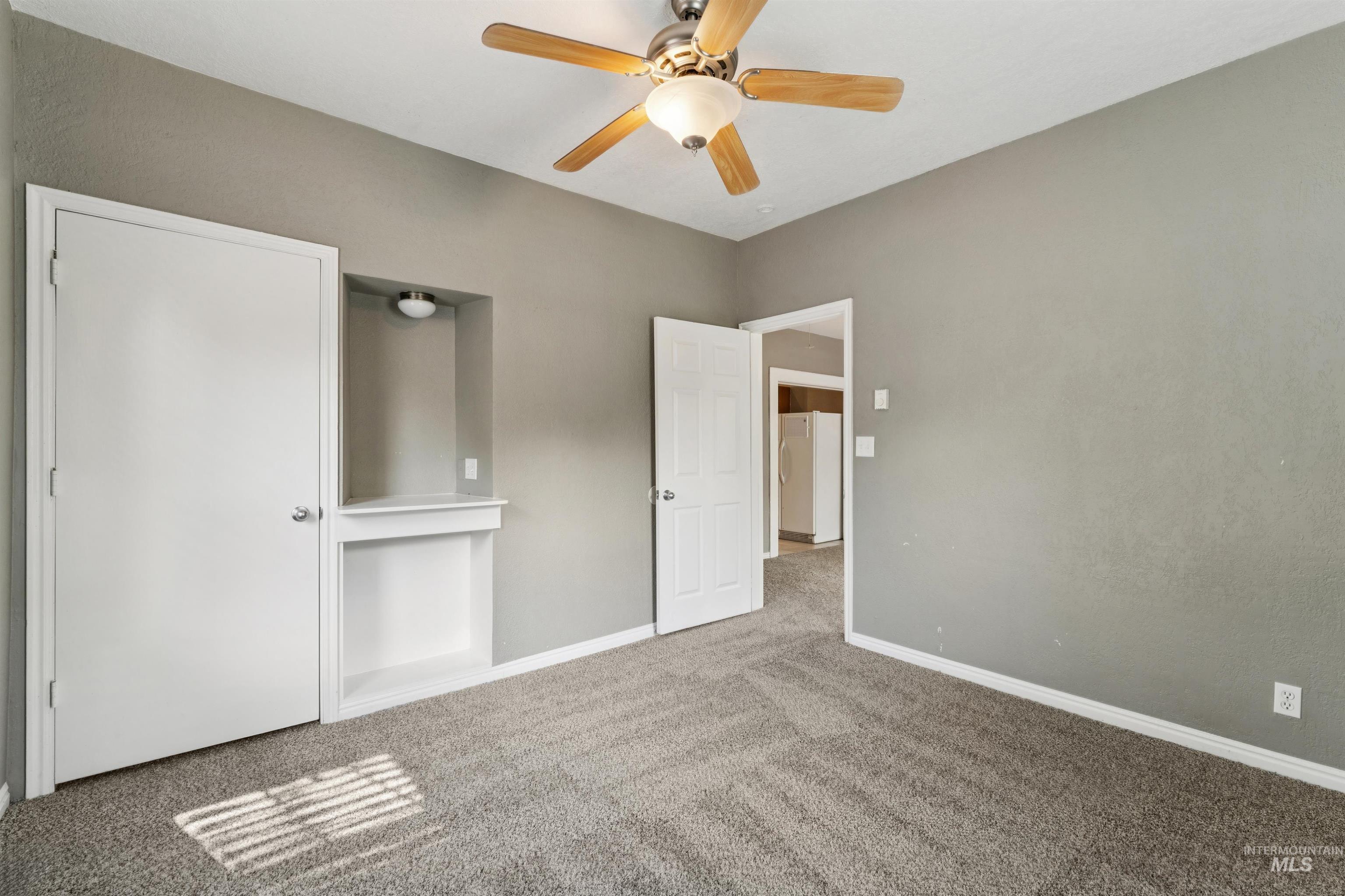 Unfurnished bedroom featuring carpet floors, freestanding refrigerator, and ceiling fan