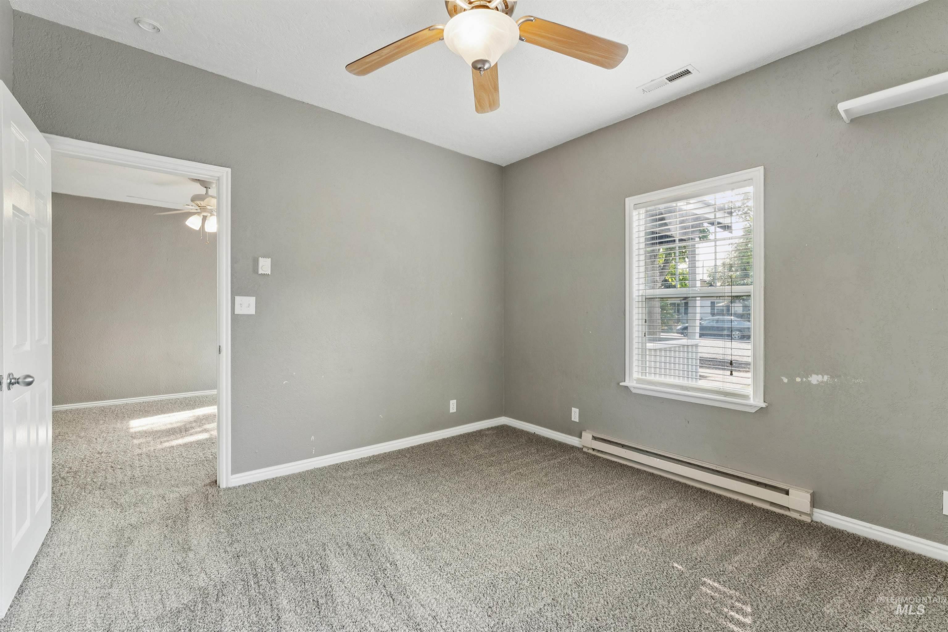 Spare room with a baseboard radiator, light colored carpet, and ceiling fan