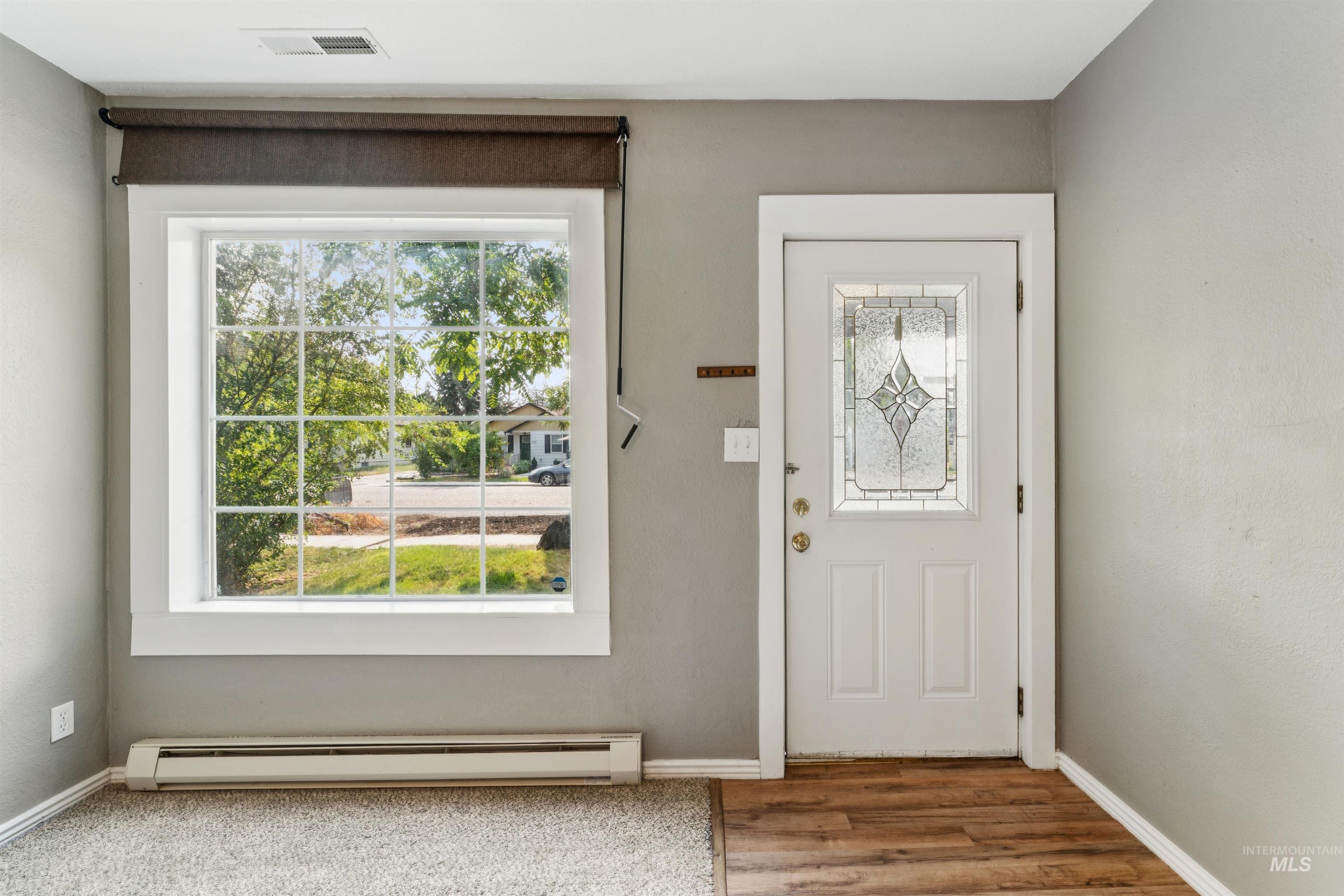 Foyer featuring a baseboard heating unit, healthy amount of natural light, and wood finished floors