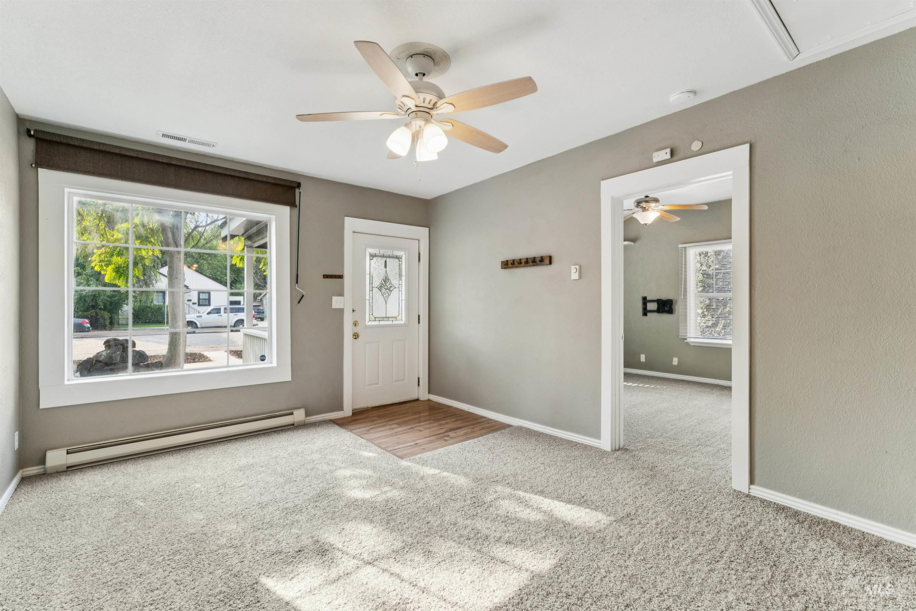Carpeted foyer with a baseboard heating unit and a ceiling fan