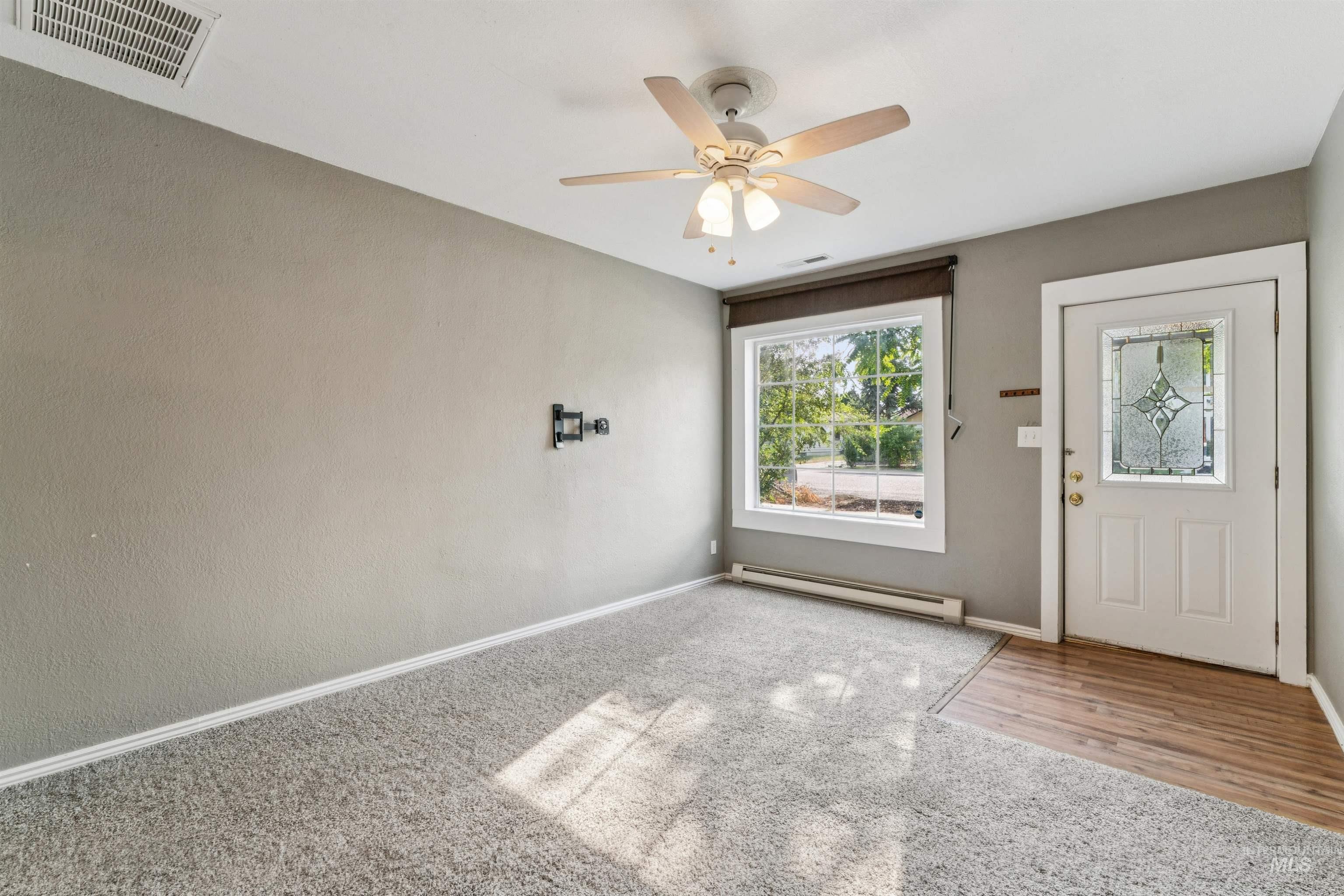 Foyer featuring baseboard heating, a ceiling fan, and carpet