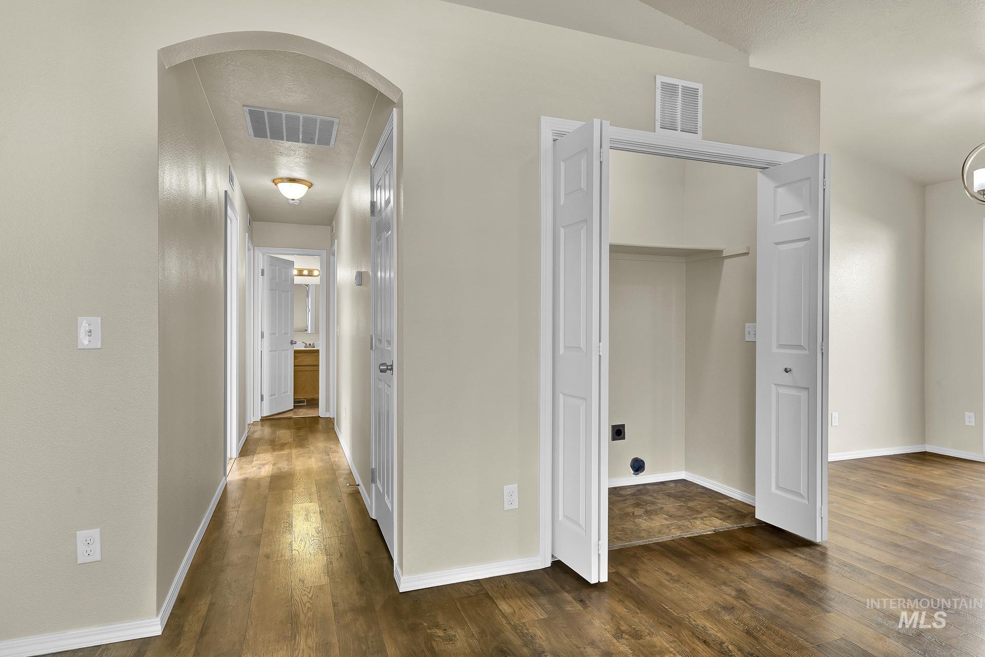 Hallway featuring dark wood-style flooring, arched walkways, and a textured ceiling