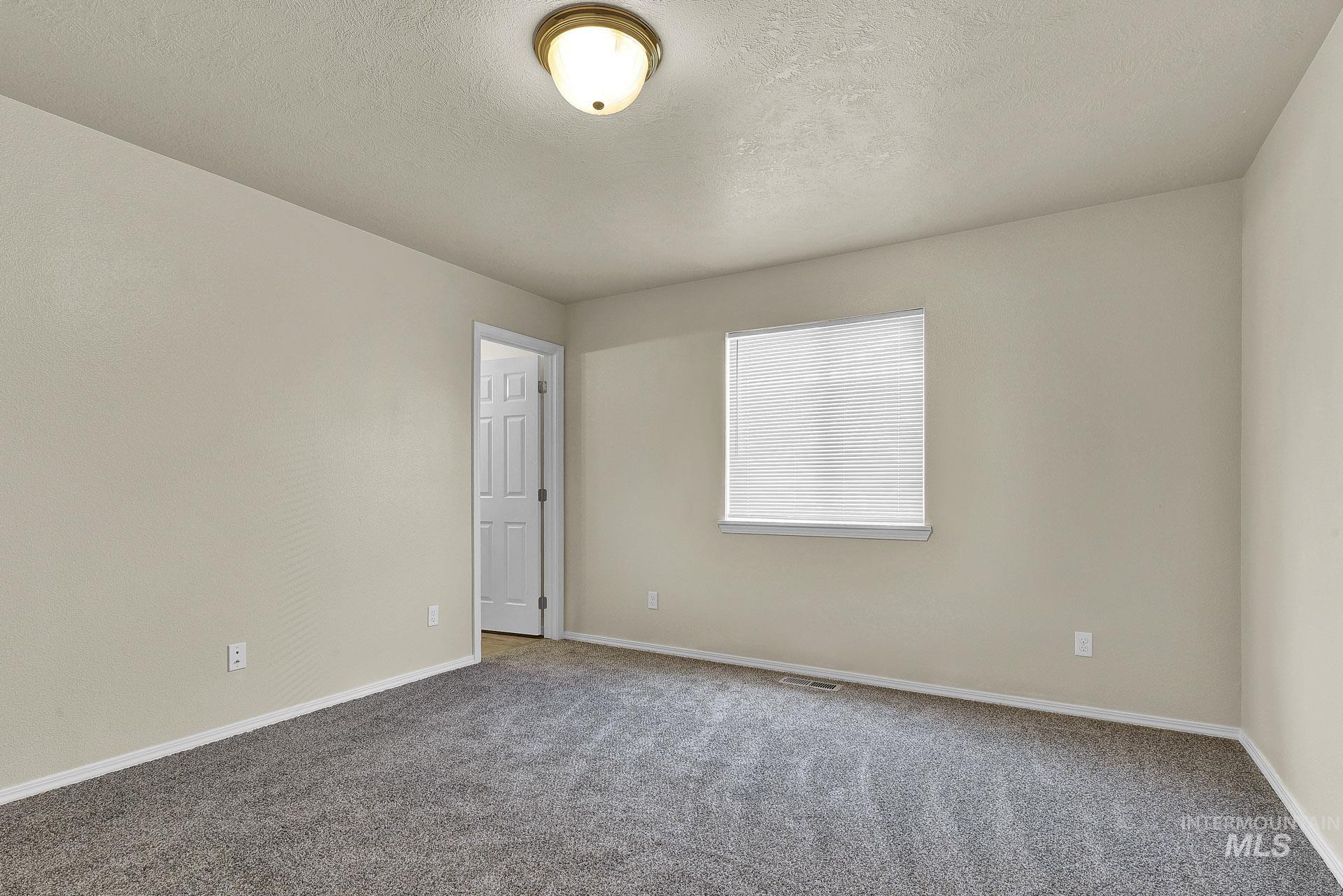 Carpeted empty room featuring baseboards and a textured ceiling