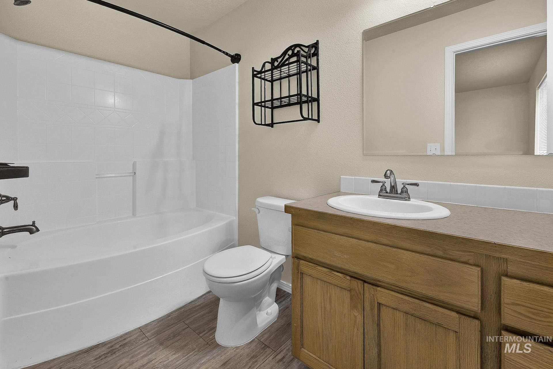 Full bathroom featuring vanity, shower / bath combination, and dark wood-style floors