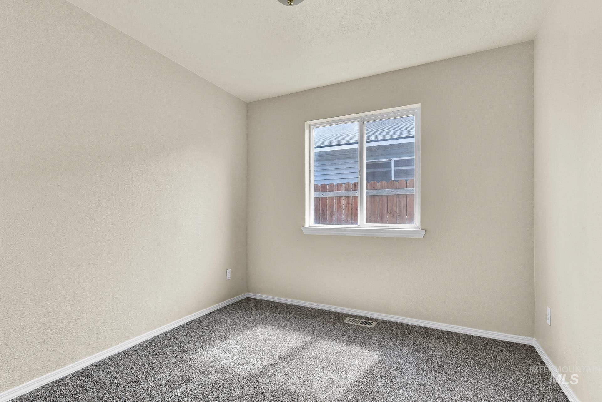 Carpeted spare room featuring baseboards