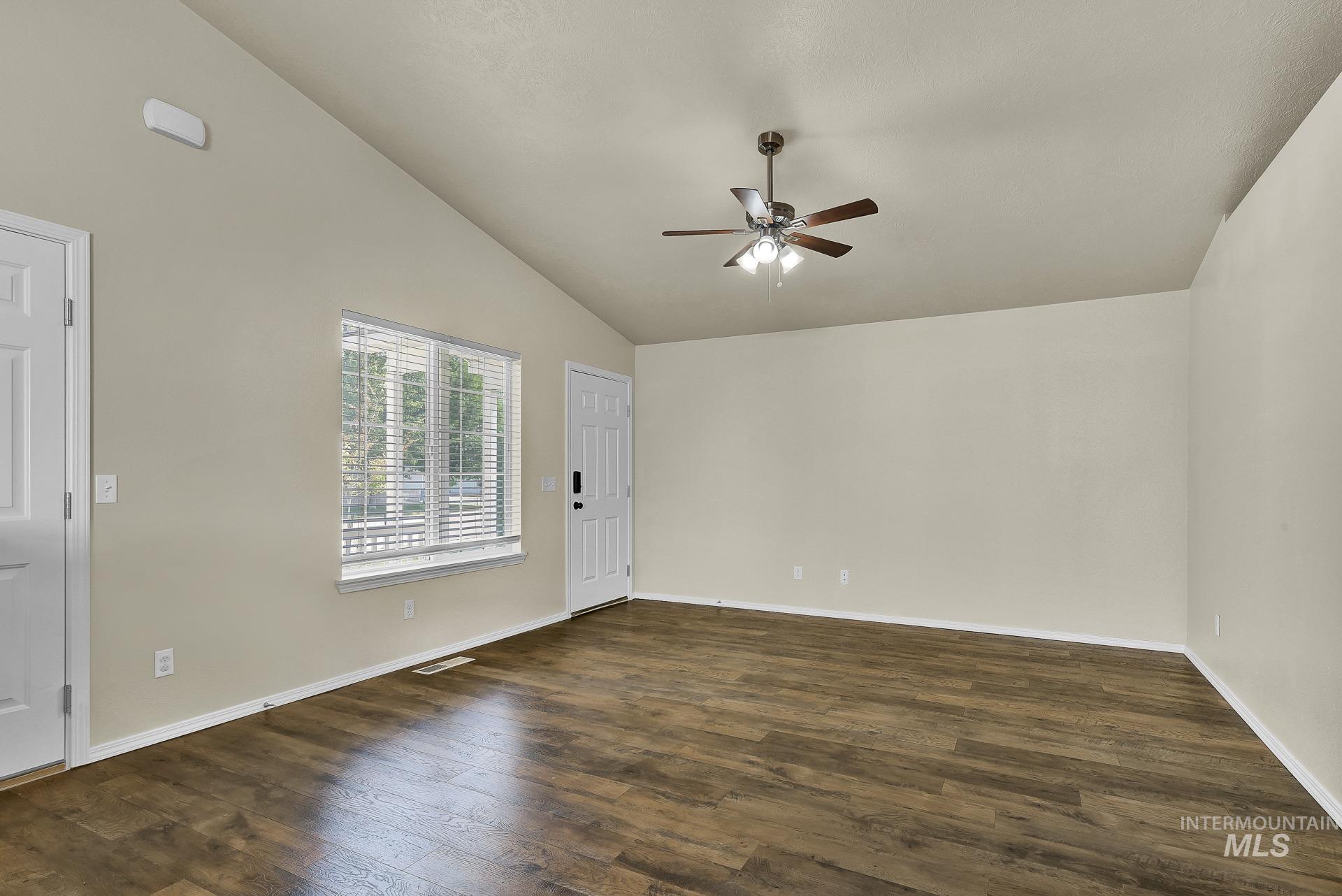 Spare room with vaulted ceiling, dark wood finished floors, and a ceiling fan