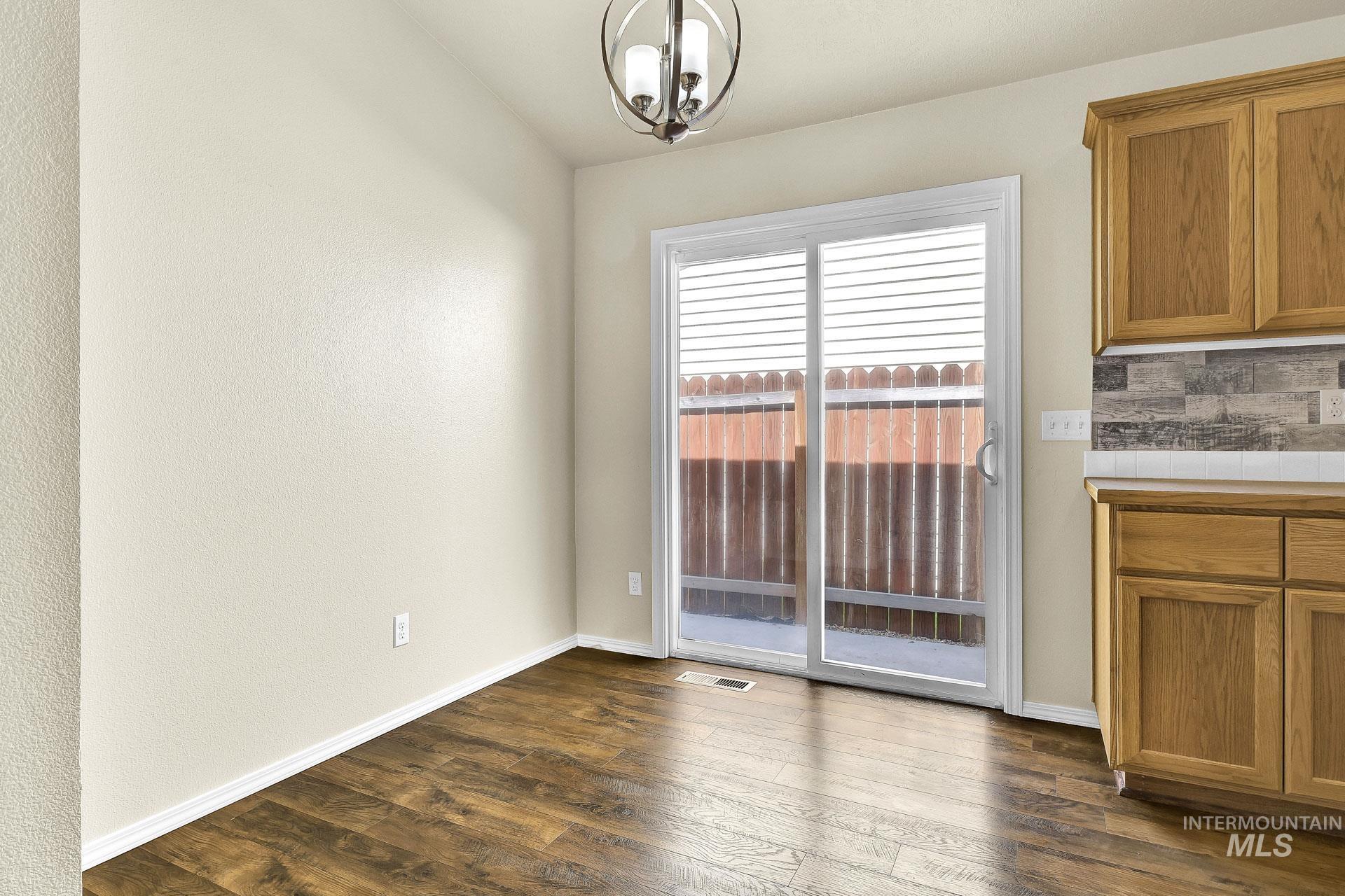 Unfurnished dining area with dark wood finished floors and baseboards
