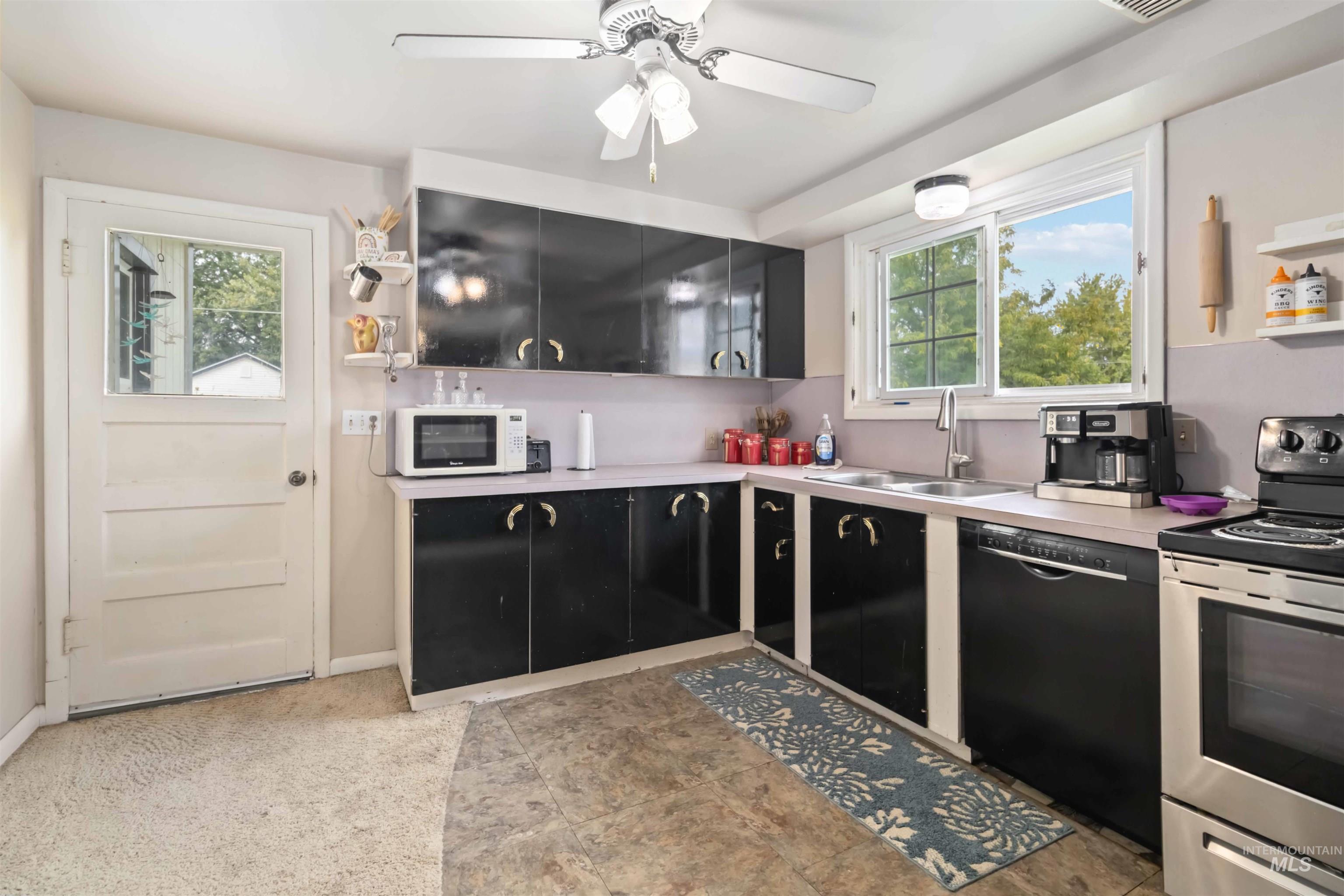 Kitchen with stainless steel electric range oven, black dishwasher, light countertops, white microwave, and ceiling fan