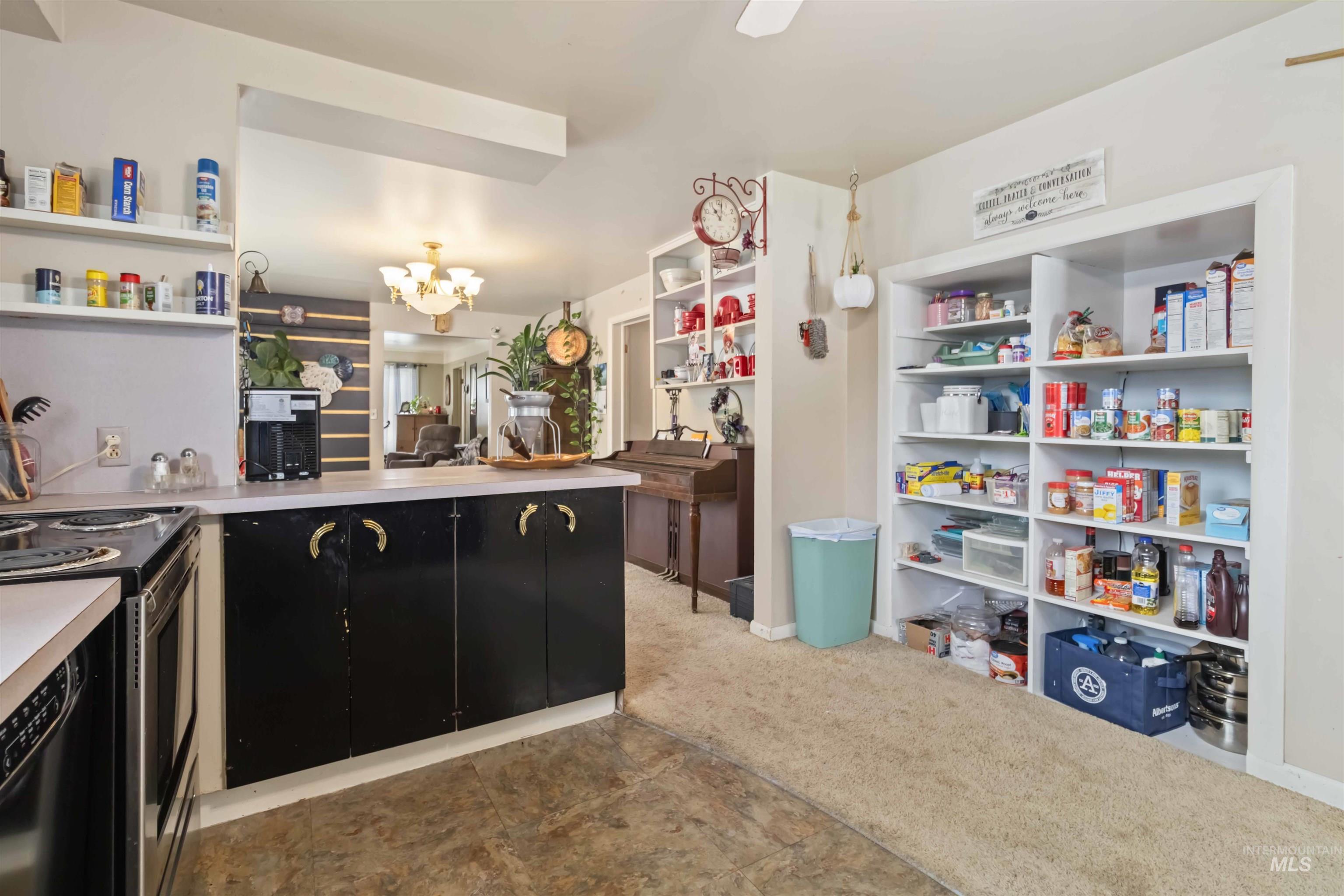Kitchen with dark cabinetry, light countertops, stainless steel range with electric stovetop, a peninsula, and a chandelier