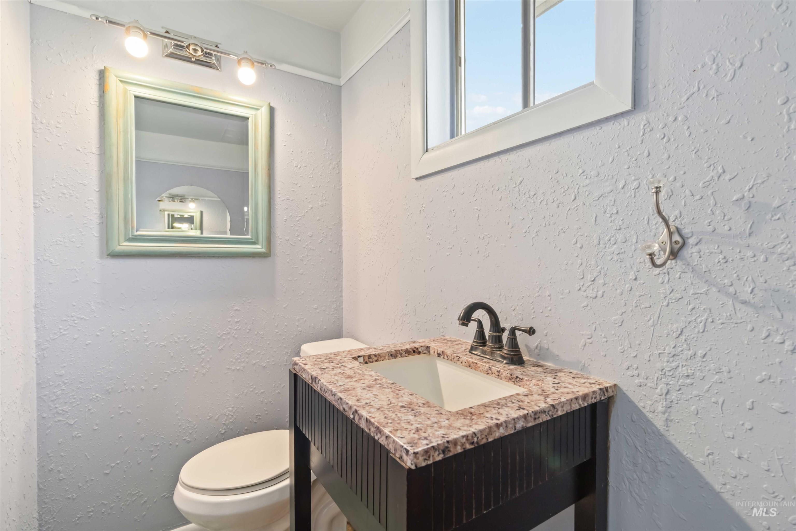 Half bathroom with a textured wall and vanity