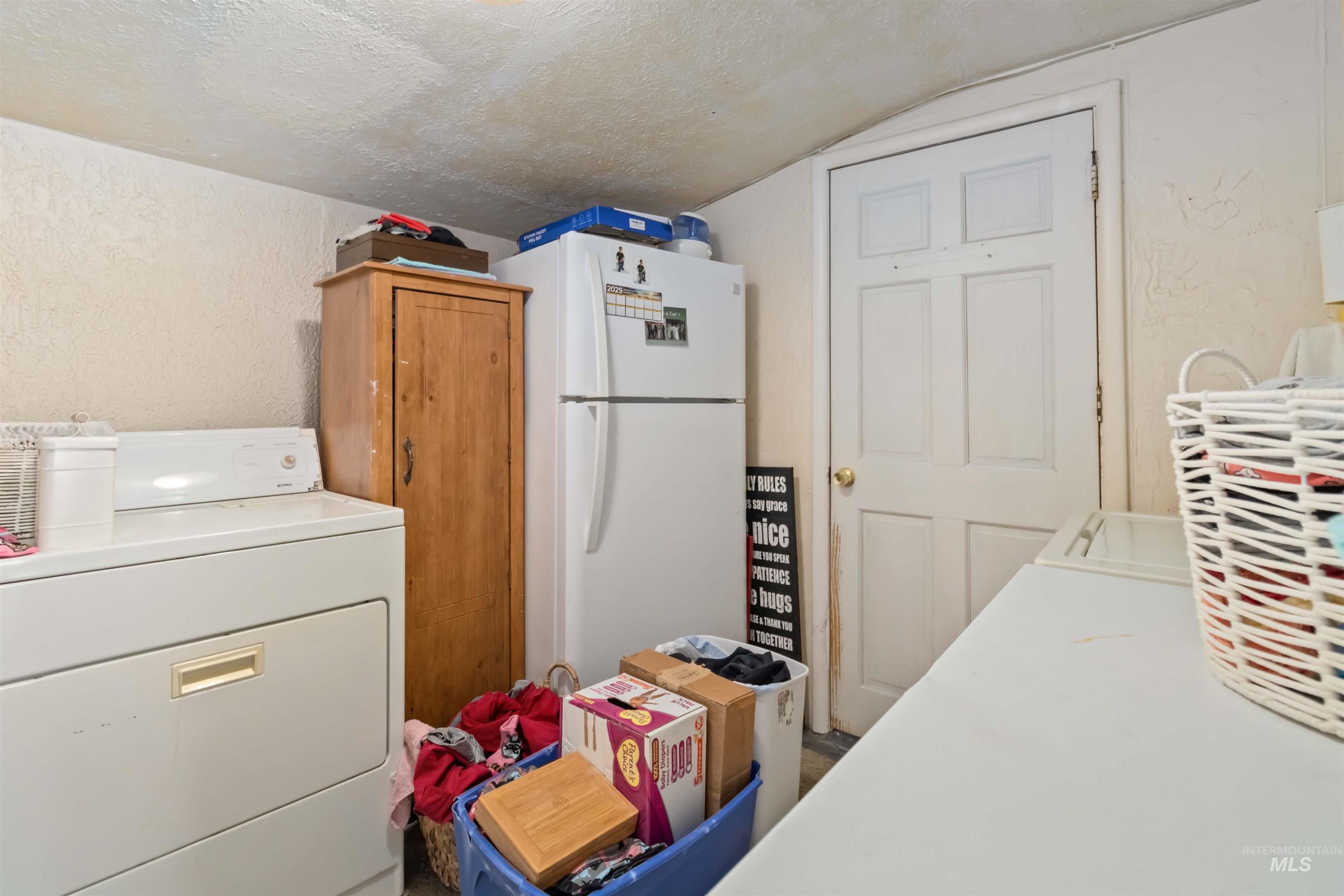 Laundry area with a textured ceiling, a textured wall, and washer and clothes dryer
