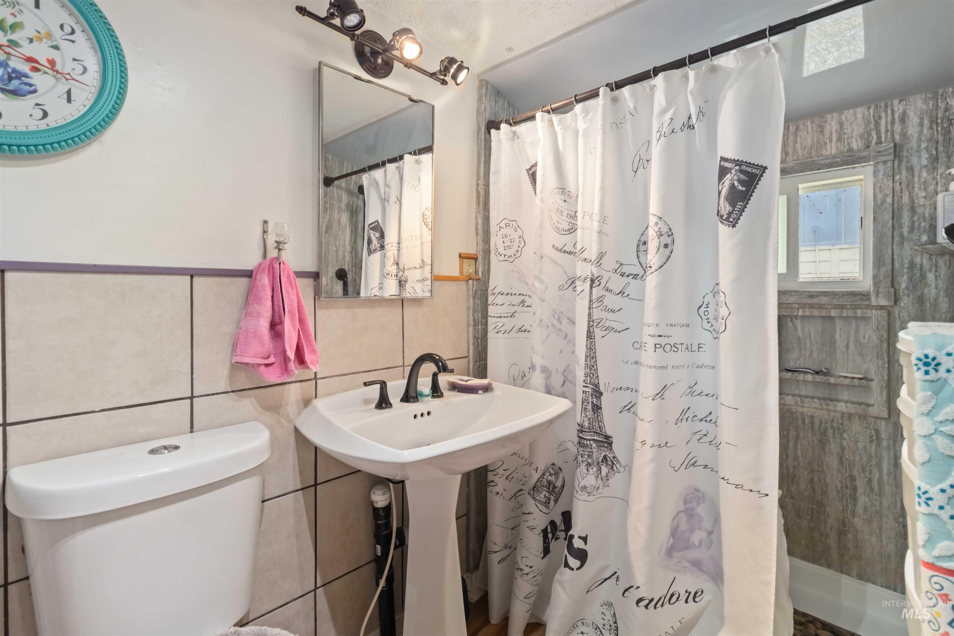 Full bath with a shower stall and tile walls