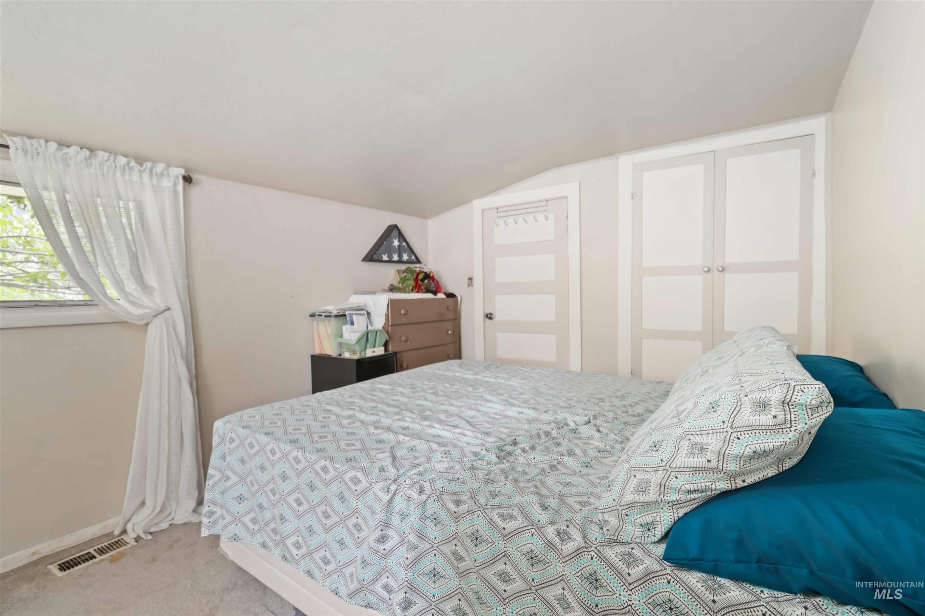 Carpeted bedroom featuring vaulted ceiling