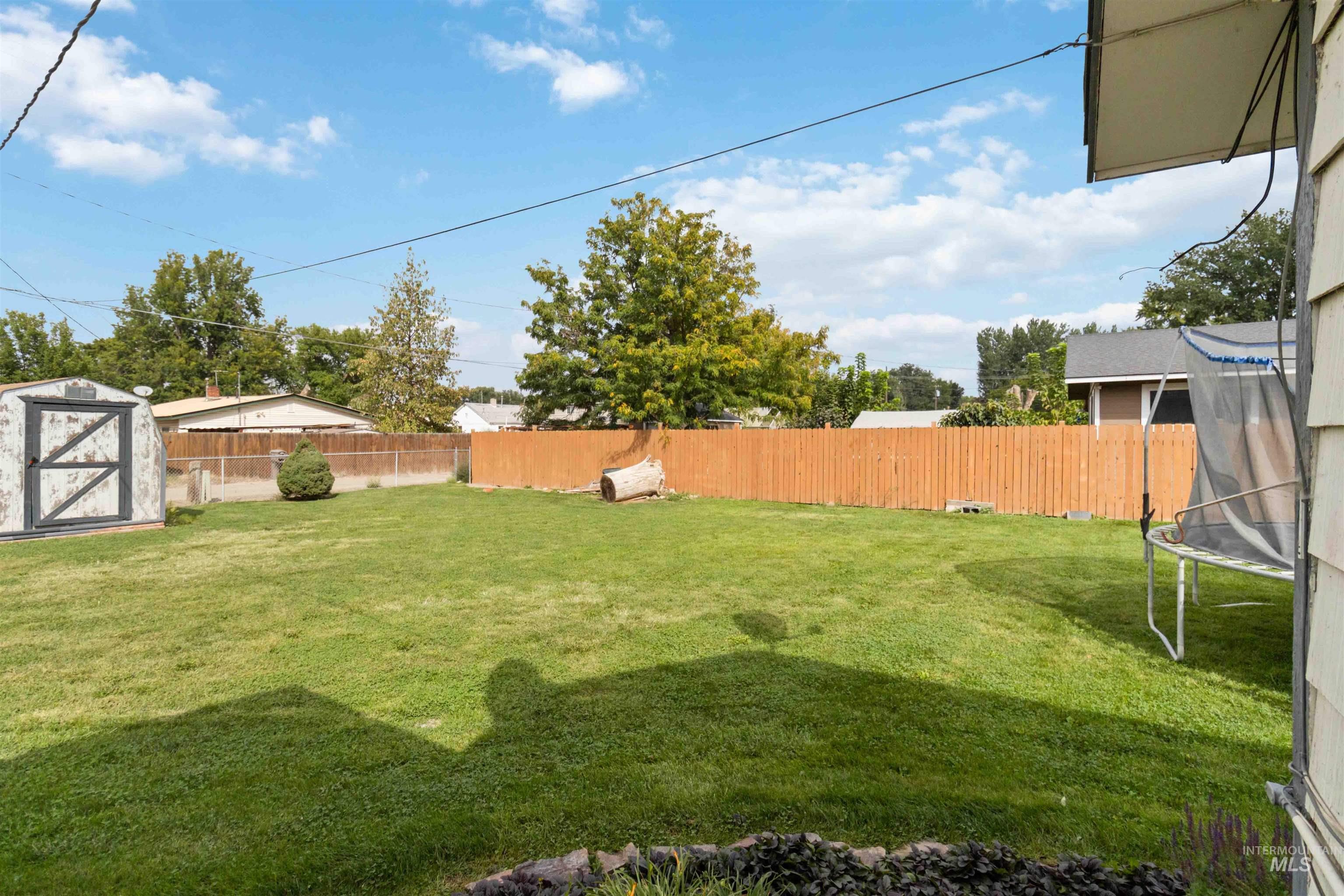 Fenced backyard with a trampoline and a storage unit