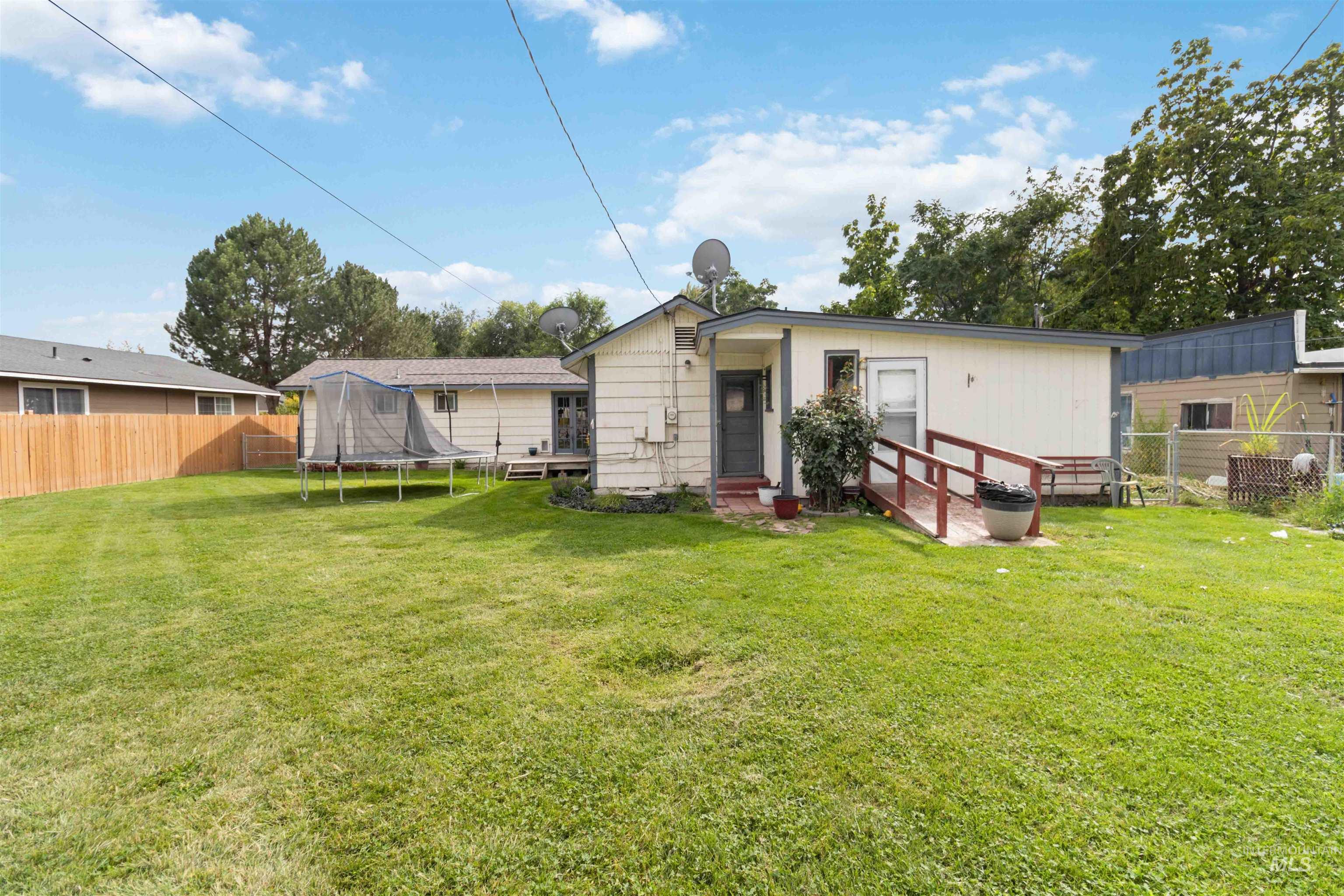 Rear view of house featuring a fenced backyard and a trampoline