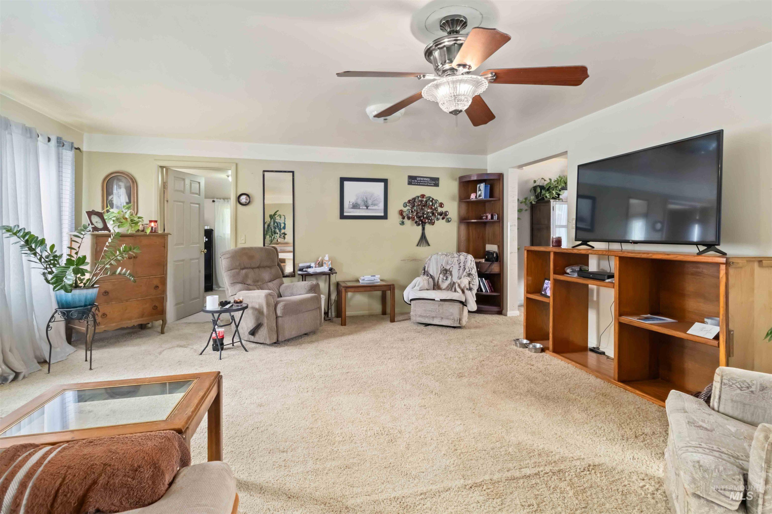 Carpeted living room with ceiling fan