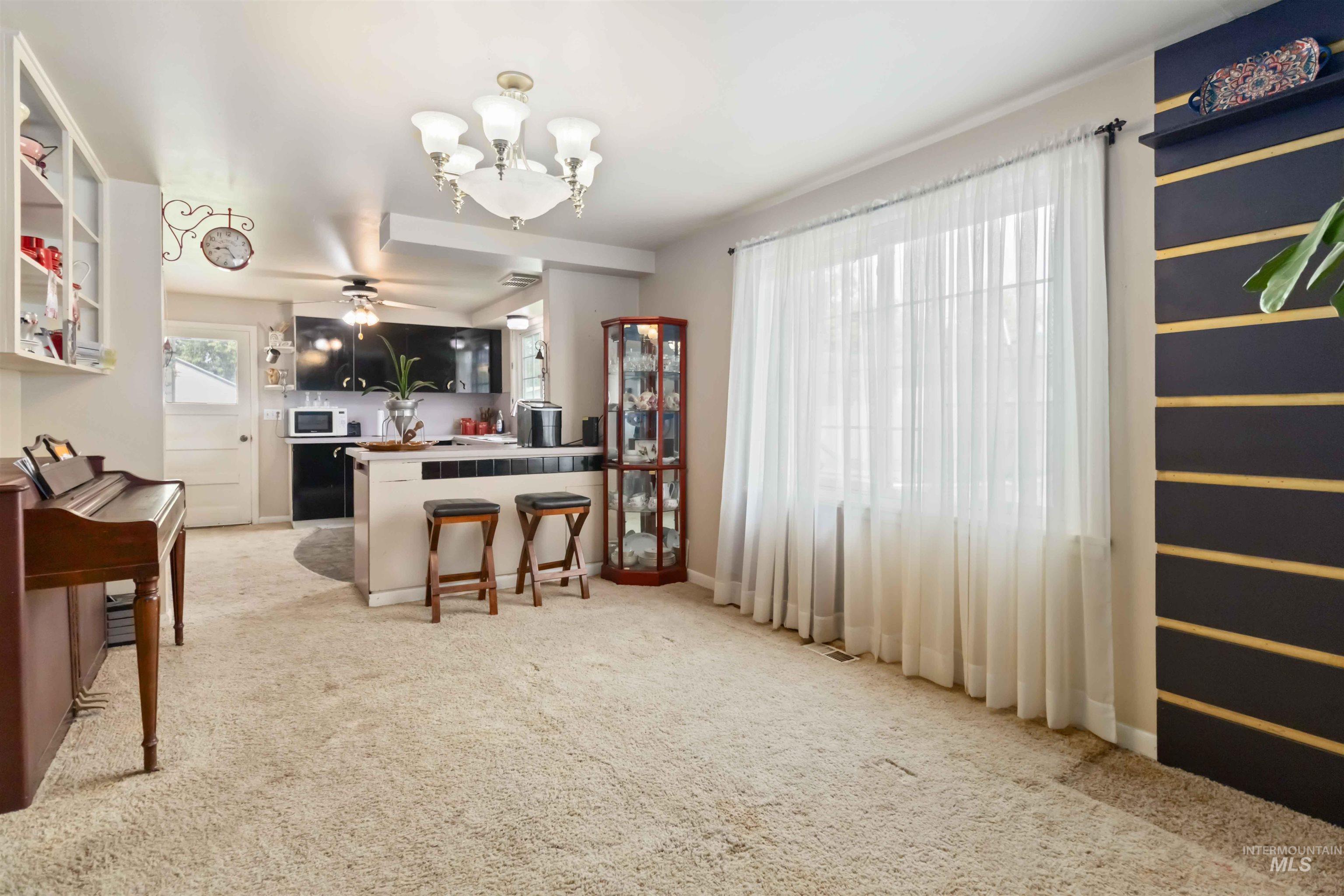 Kitchen with a peninsula, a breakfast bar, a chandelier, light carpet, and white microwave