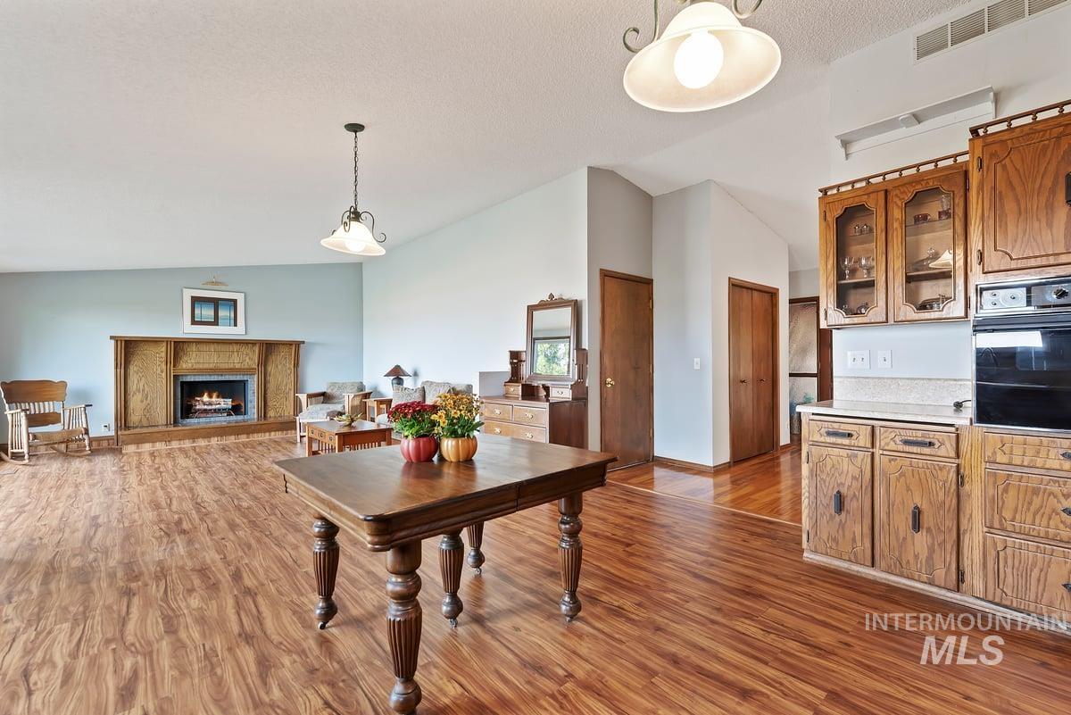 Dining space featuring vaulted ceiling, dark wood-type flooring, a lit fireplace, and a textured ceiling