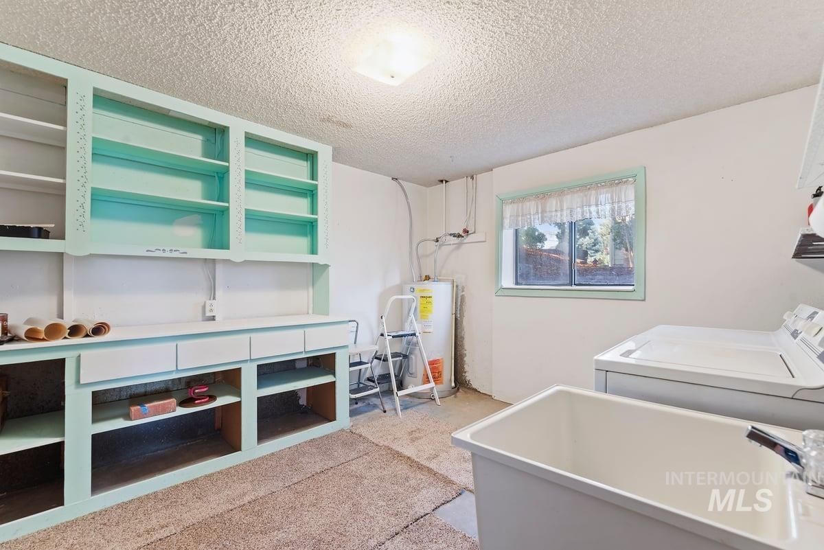 Laundry area with a textured ceiling, water heater, and separate washer and dryer
