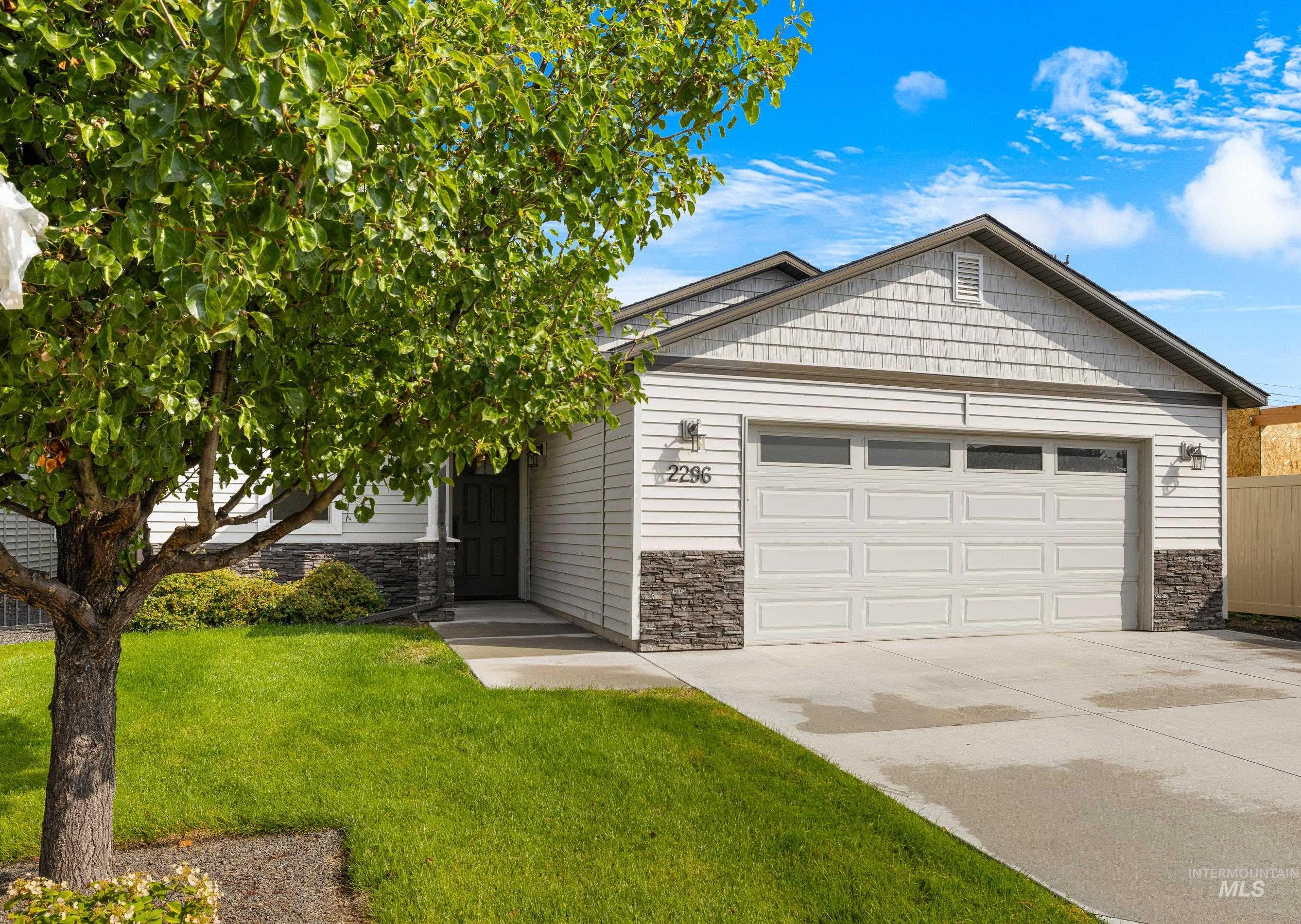 View of front of house with stone siding, driveway, a front lawn, and a garage