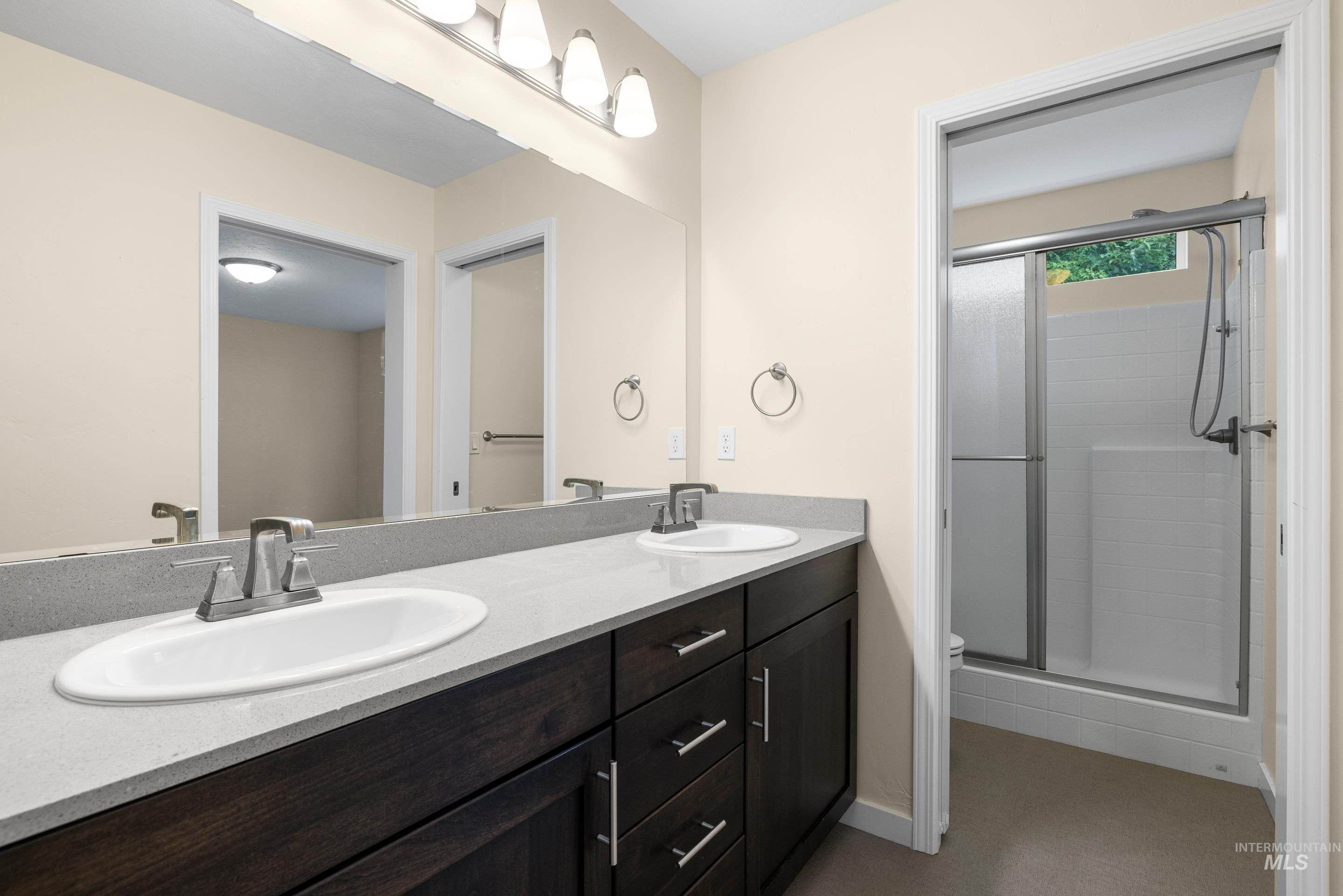 Full bathroom featuring double vanity and a shower stall