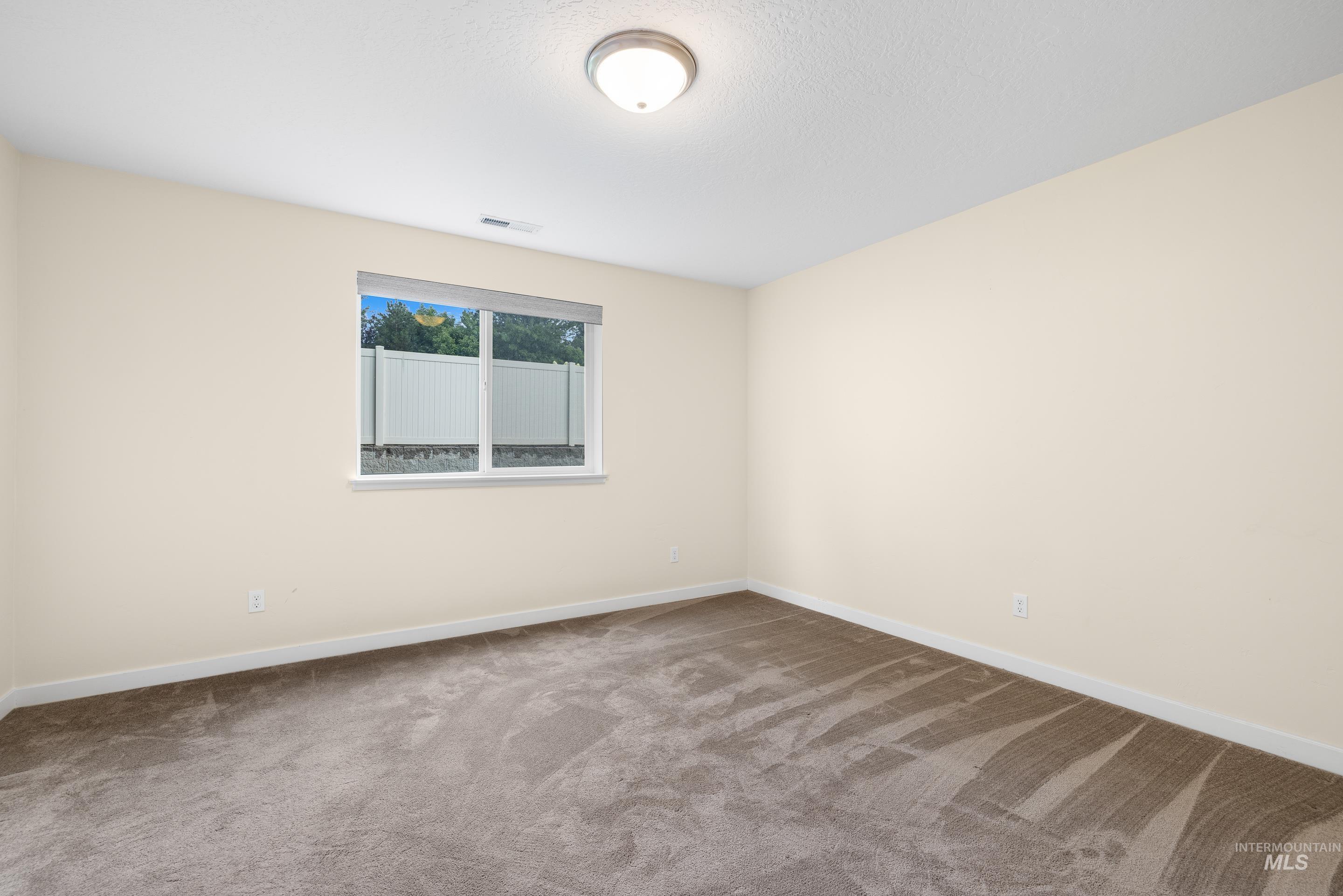 Carpeted spare room featuring baseboards and a textured ceiling