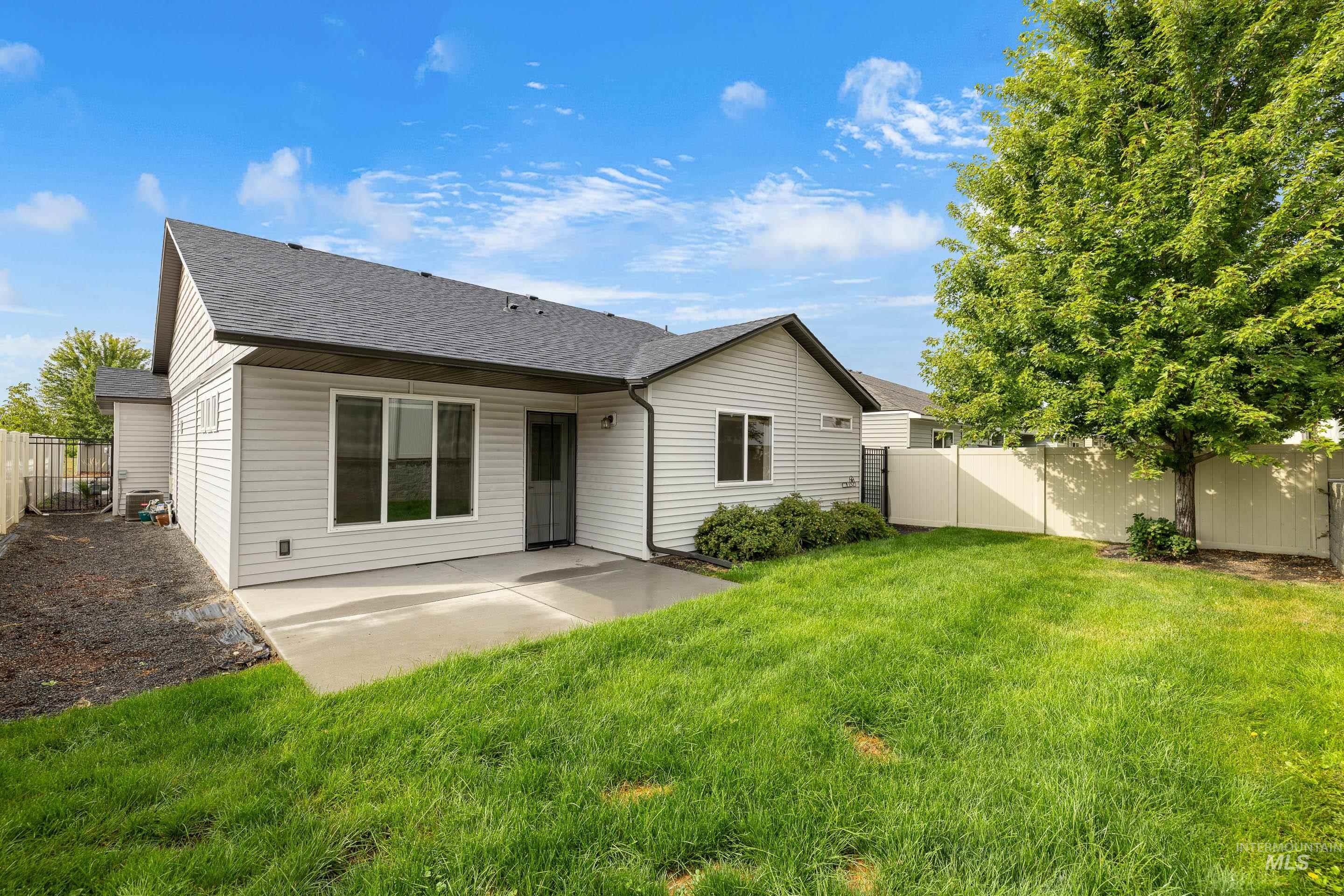 Rear view of house with a shingled roof, a patio area, and a fenced backyard