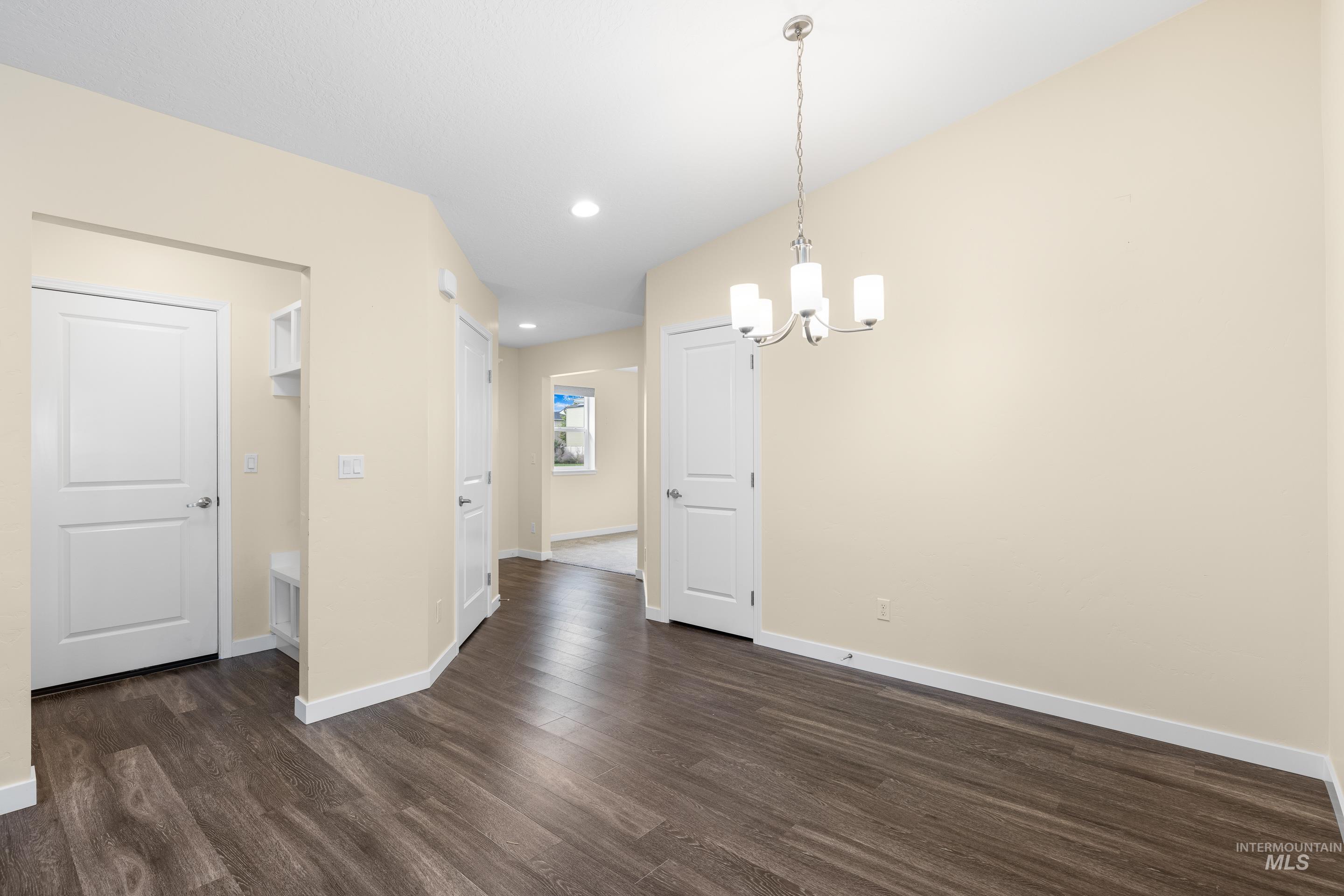 Unfurnished dining area with dark wood-style floors, a chandelier, and recessed lighting