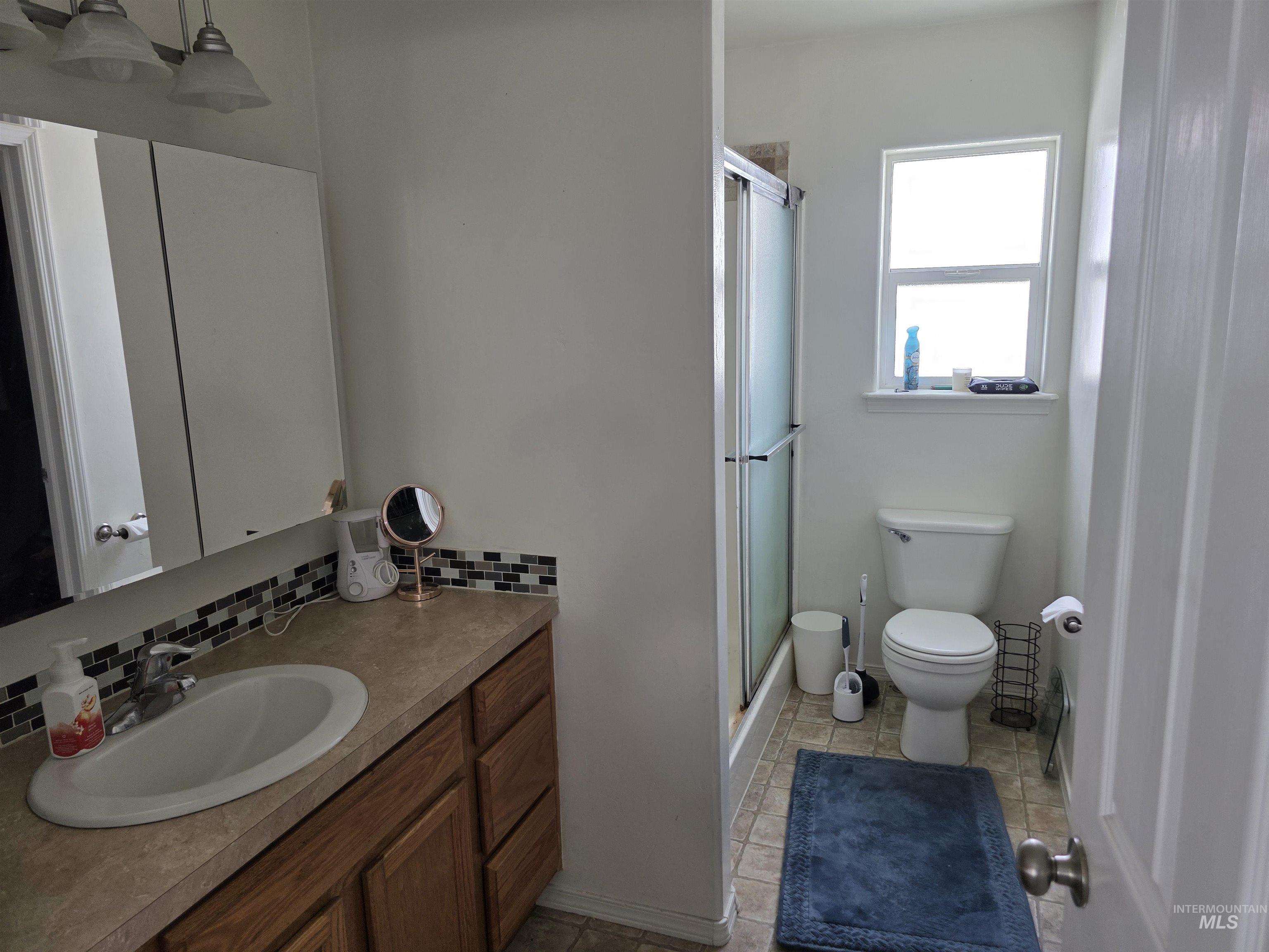 Full bathroom with vanity, a shower stall, tasteful backsplash, and light tile patterned floors