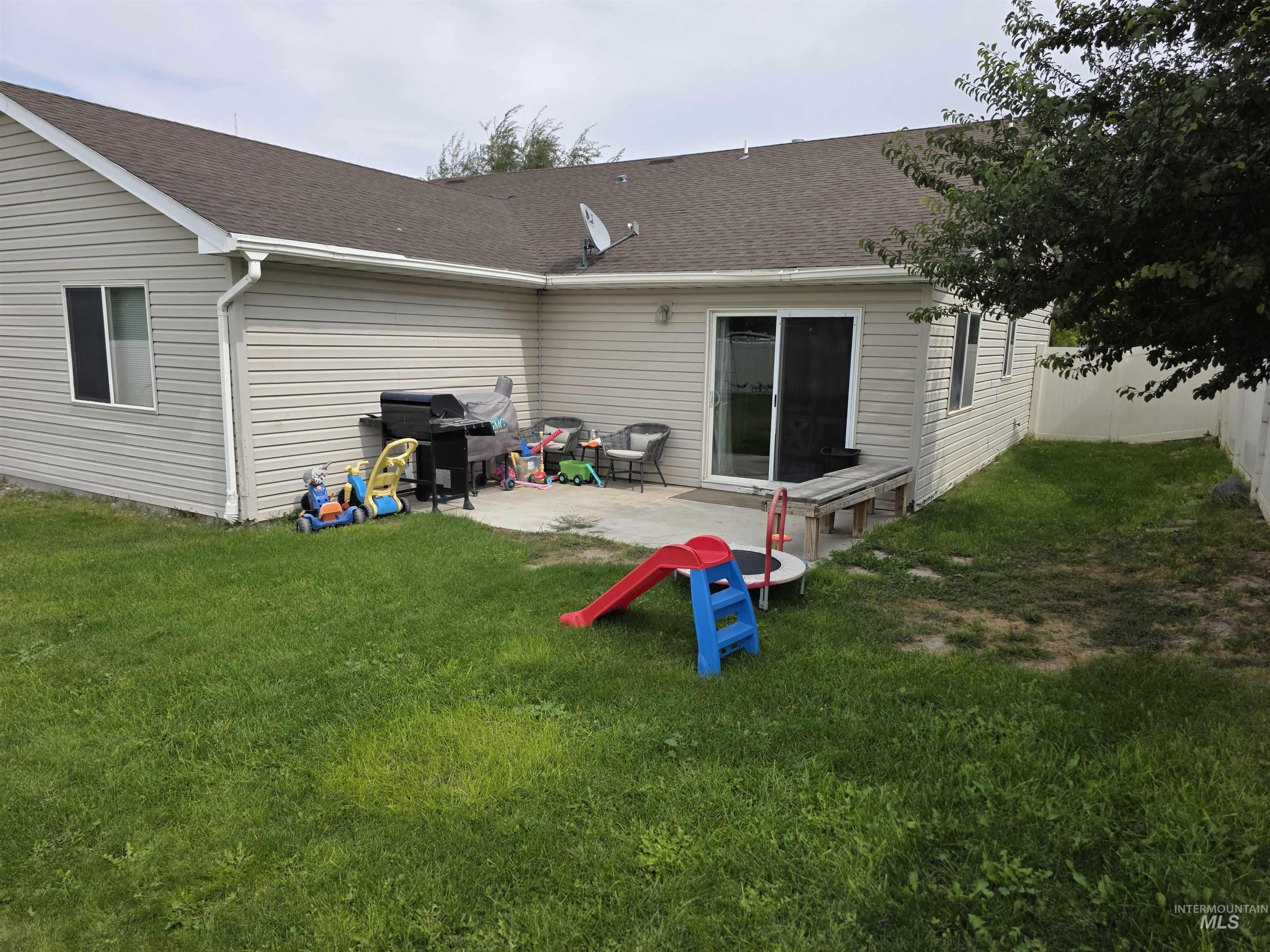 Rear view of house with a shingled roof and a patio area