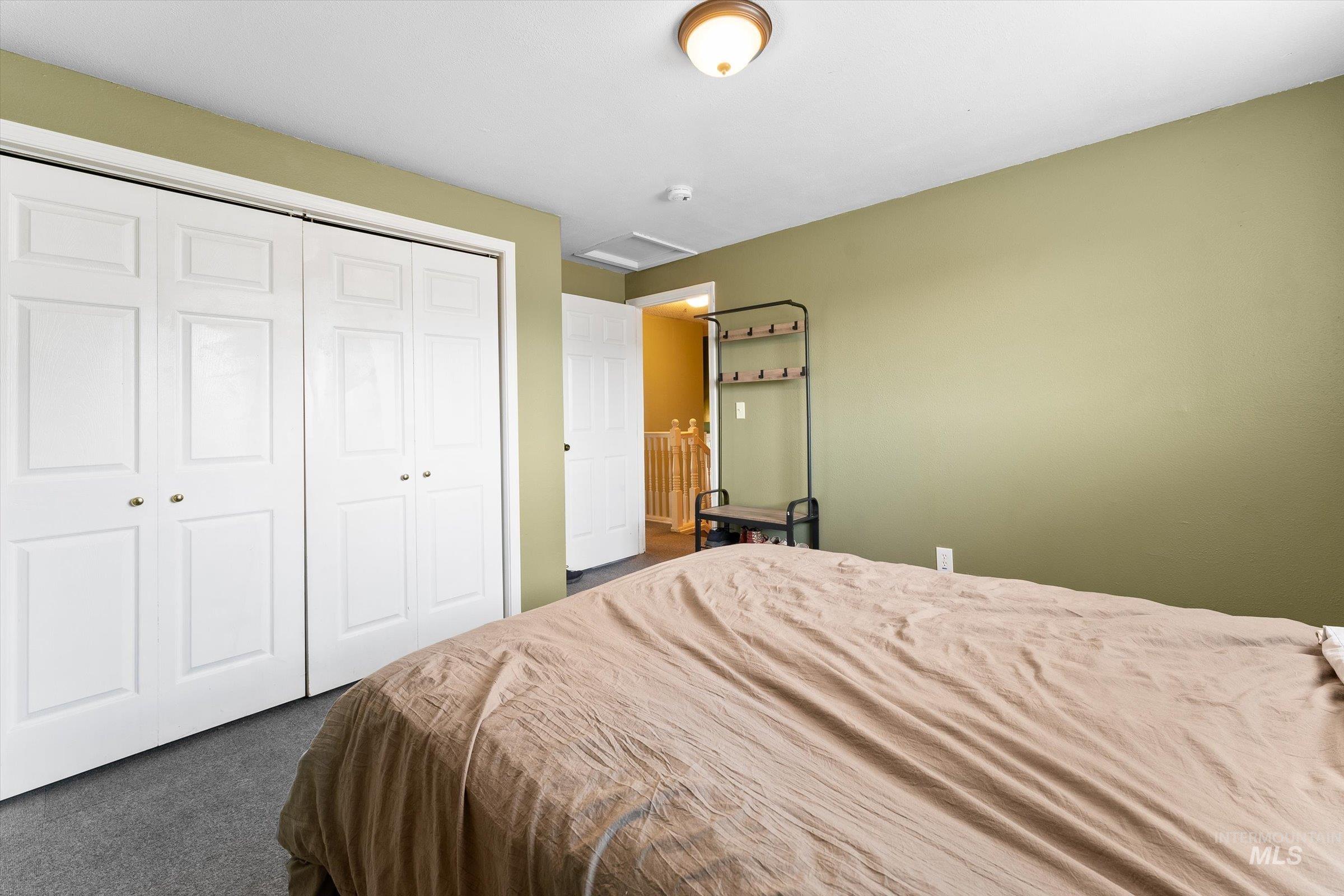 Bedroom with attic access, dark carpet, and a closet
