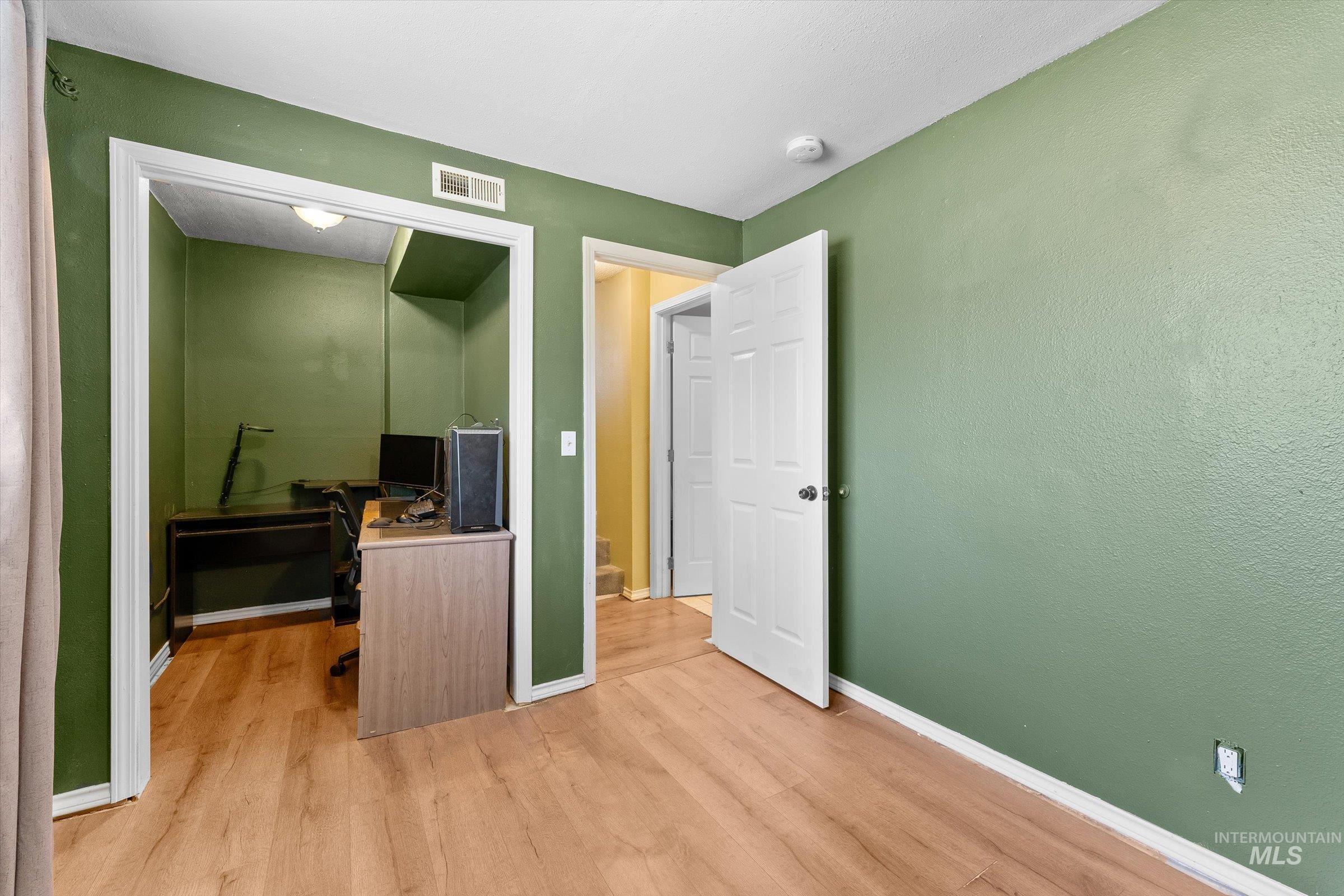 Bedroom with wood finished floors and an office area