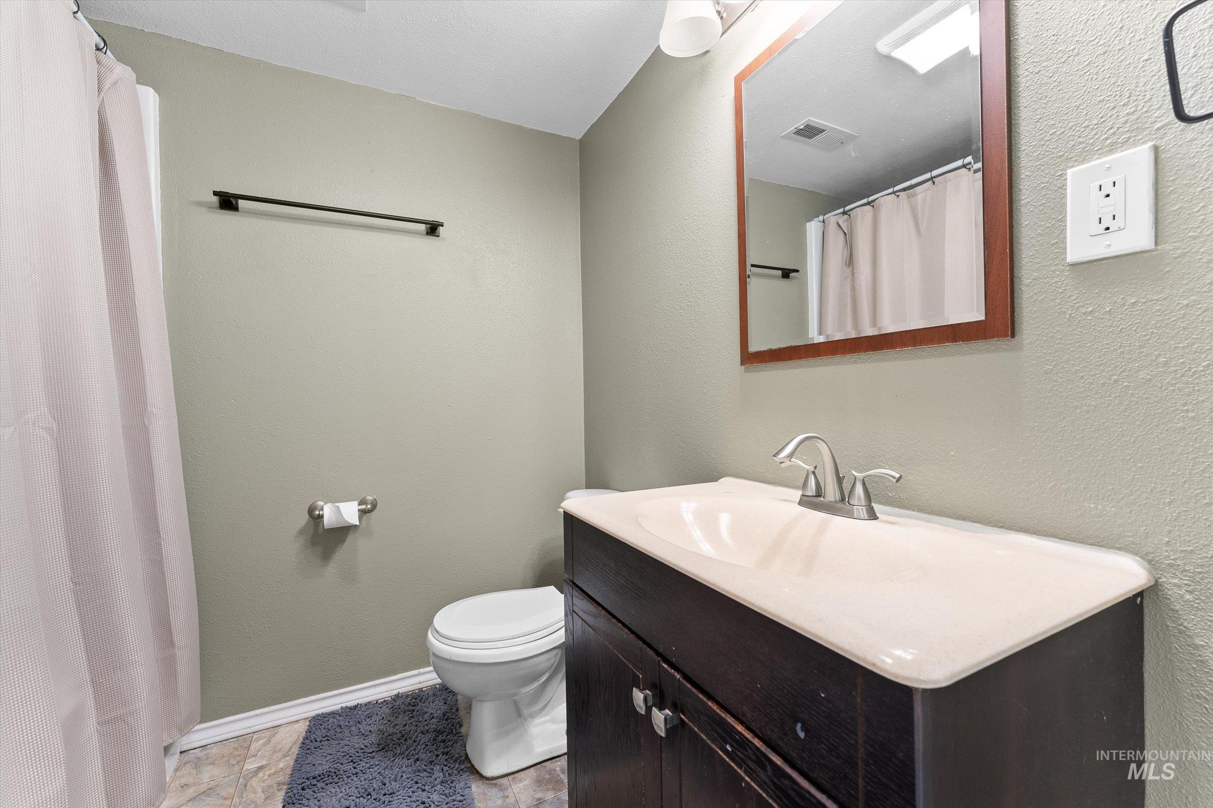 Full bathroom featuring vanity, a textured wall, and a shower with curtain