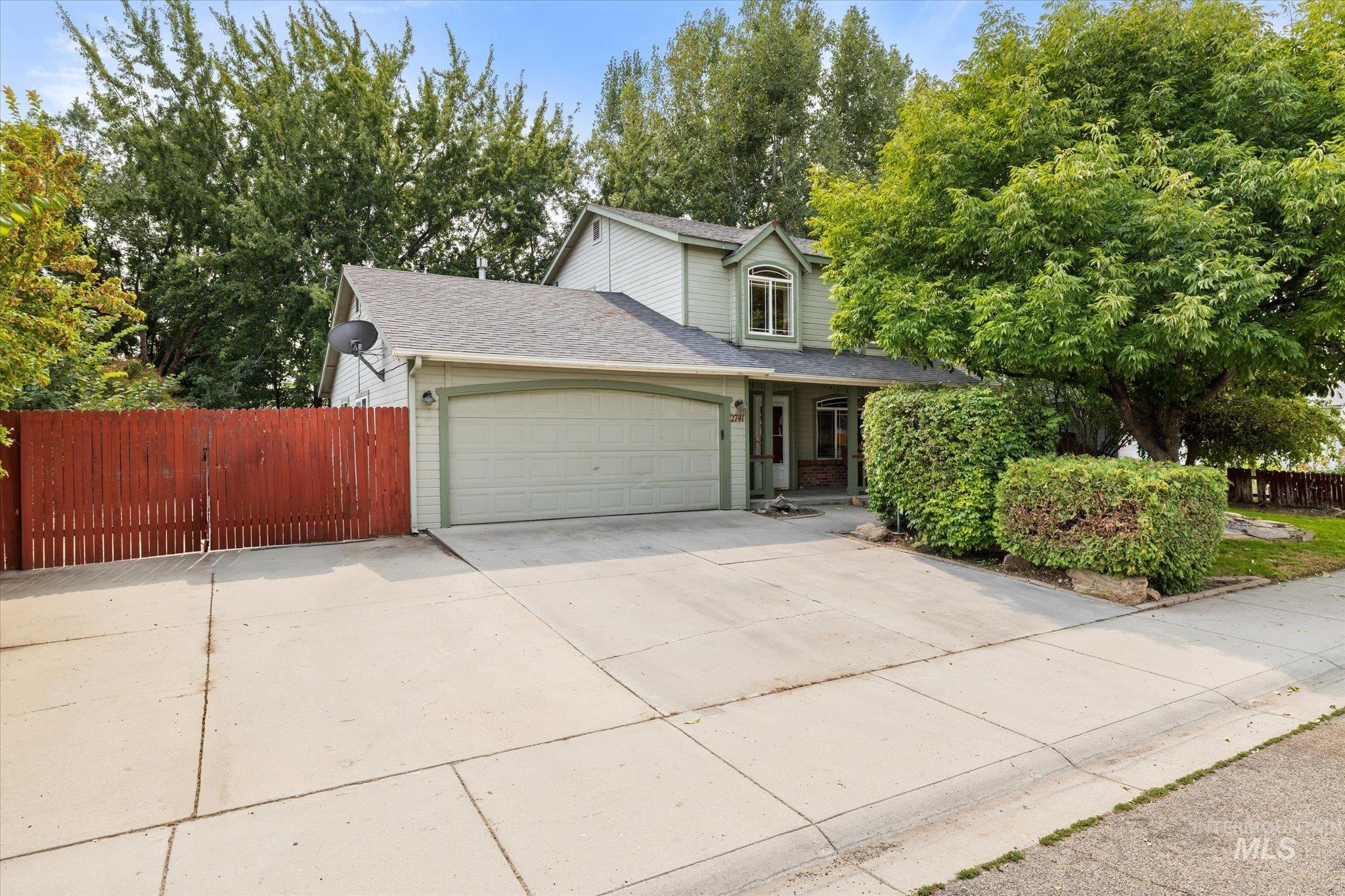 Traditional-style house with roof with shingles, driveway, an attached garage, and covered porch