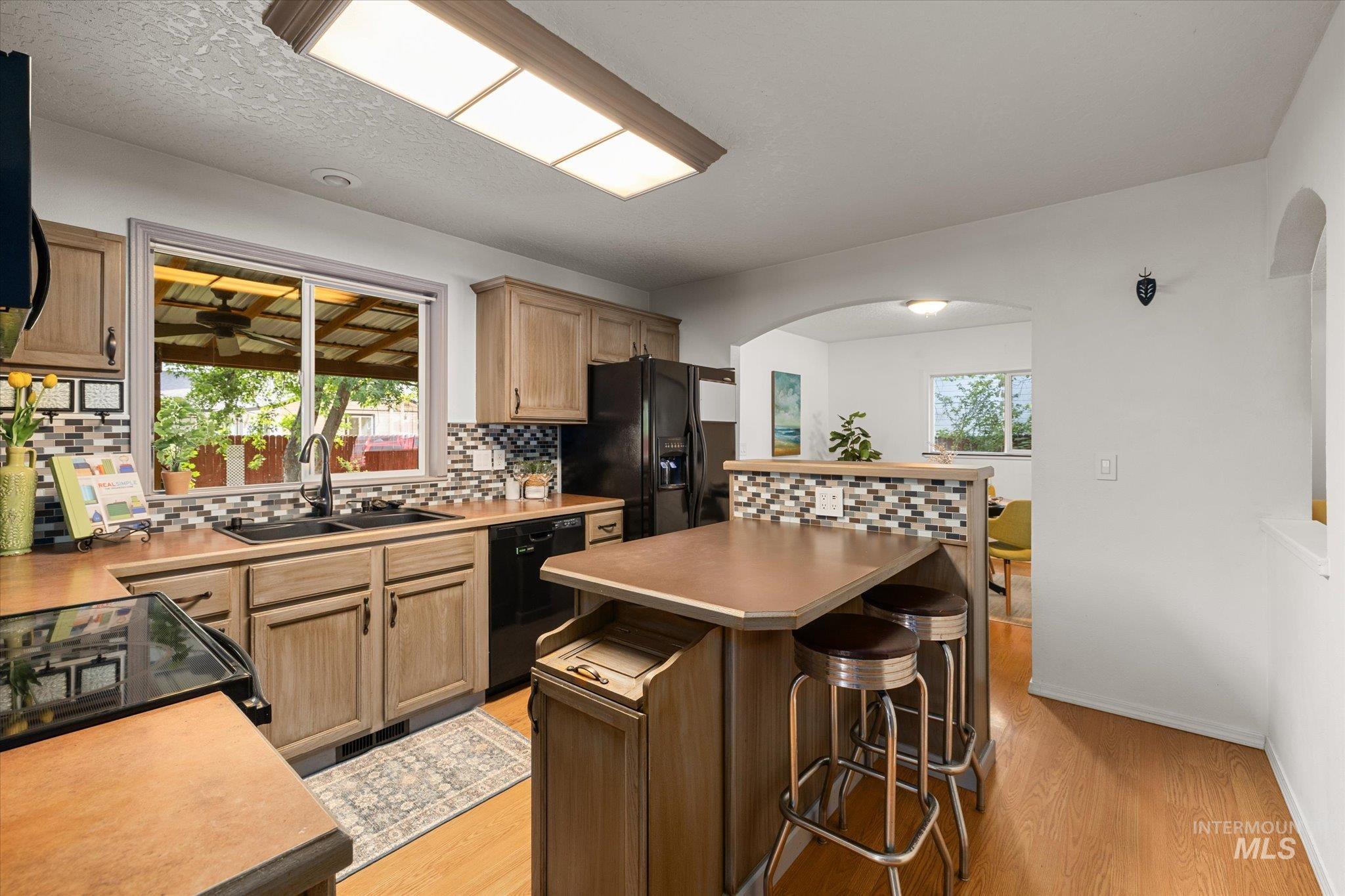 Kitchen featuring tasteful backsplash, a breakfast bar area, light wood-type flooring, a center island, and a textured ceiling