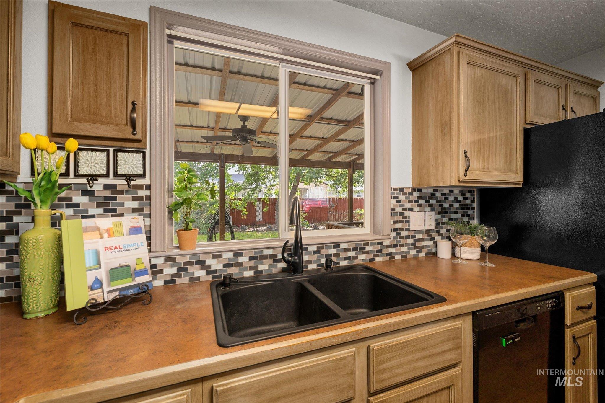 Kitchen featuring decorative backsplash, black appliances, ceiling fan, light brown cabinets, and a textured ceiling
