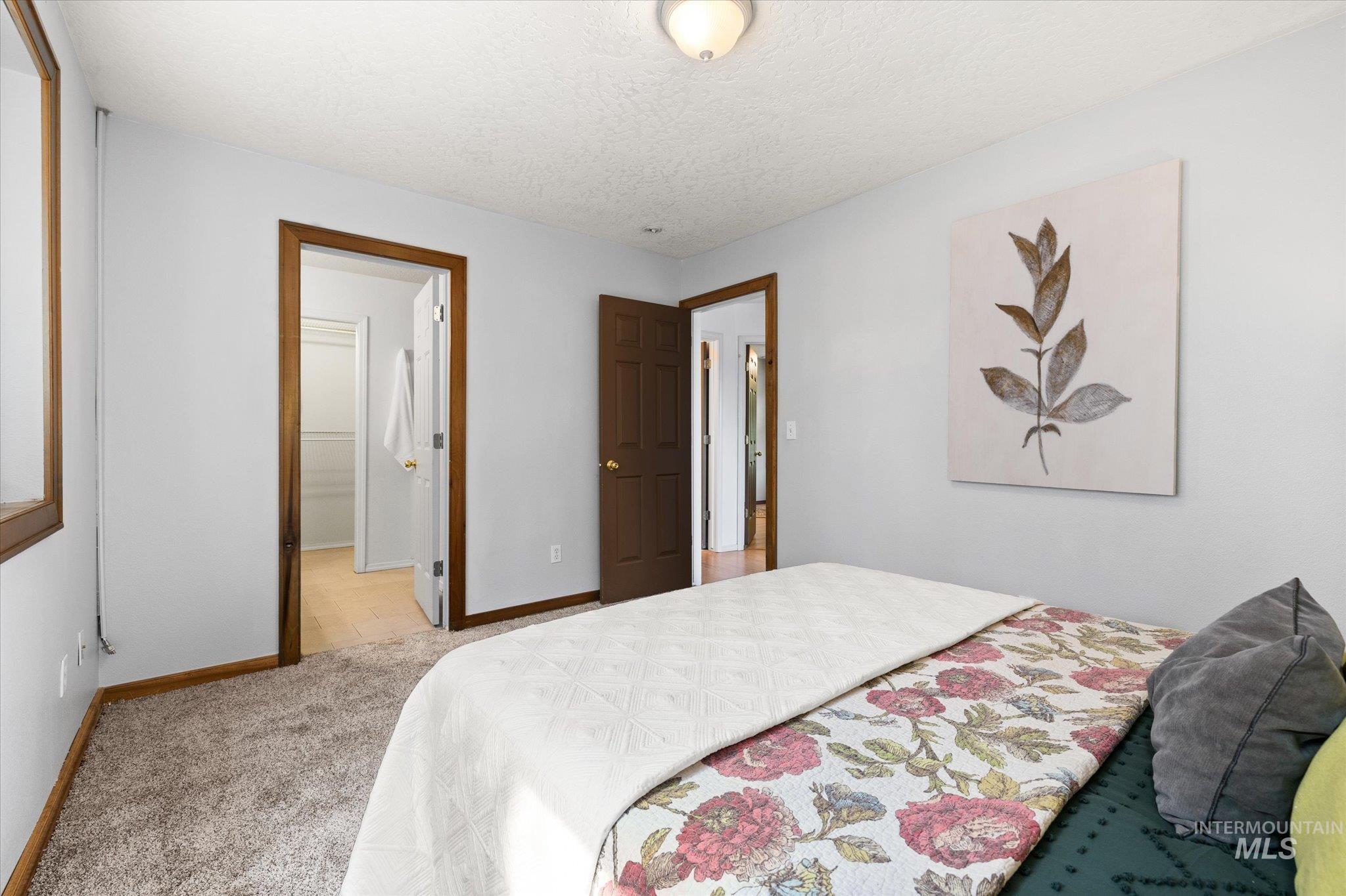 Bedroom featuring light carpet, a textured ceiling, and ensuite bath