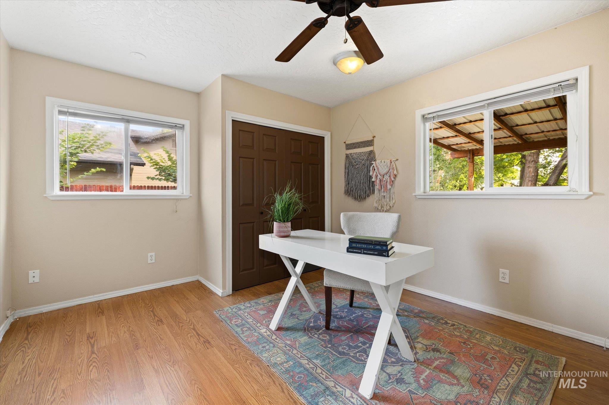 Office with ceiling fan, healthy amount of natural light, and light wood-style floors
