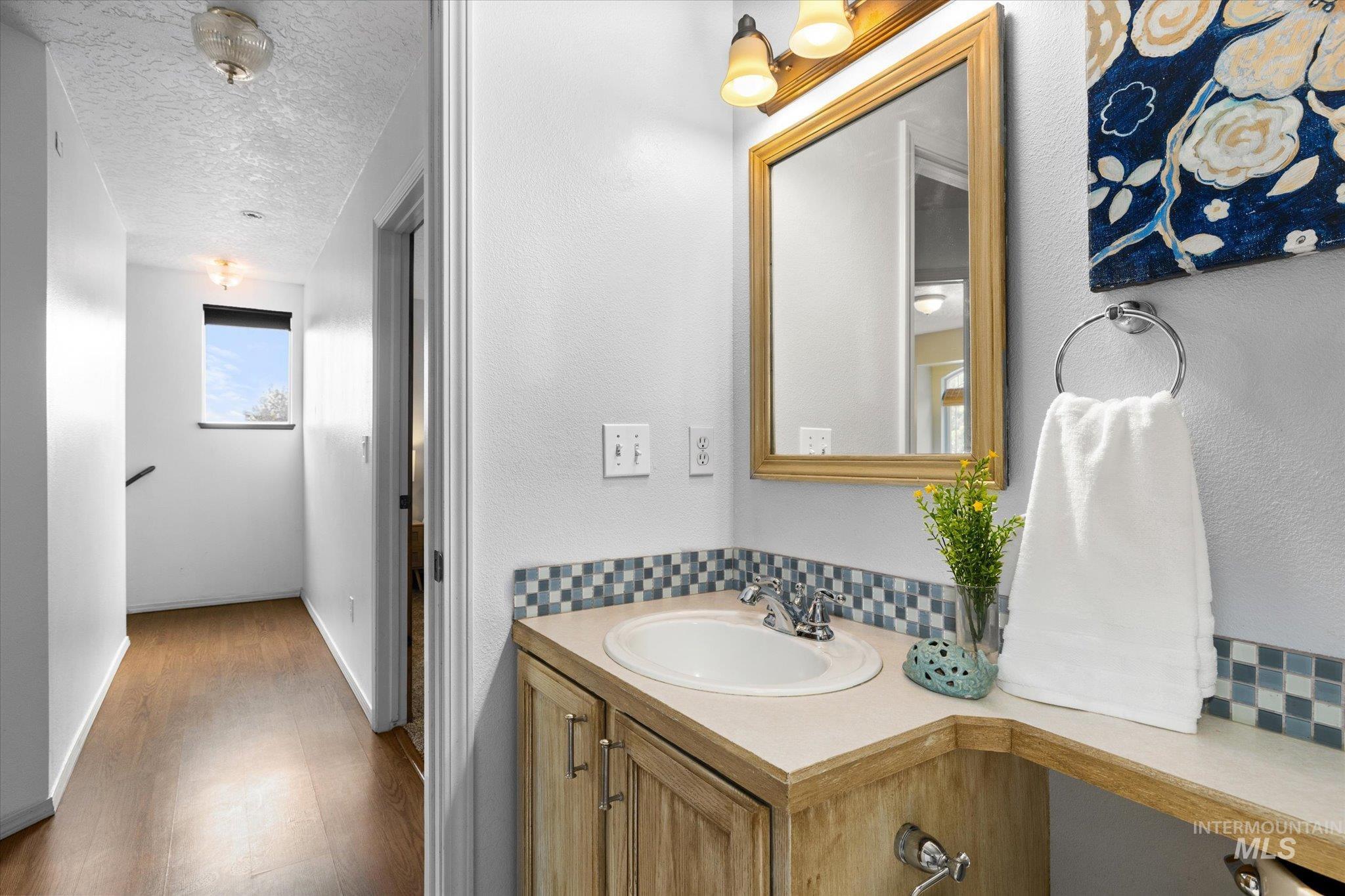 Bathroom with a textured ceiling, vanity, and wood finished floors