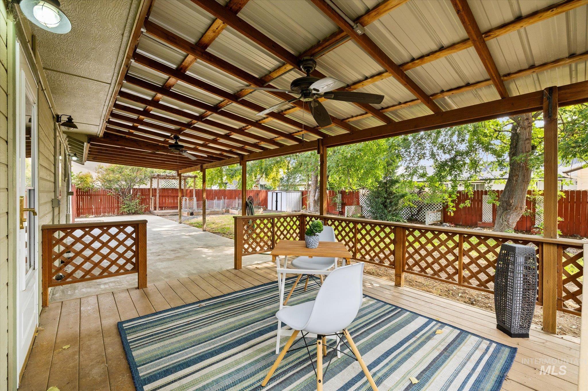 Wooden deck featuring ceiling fan, a fenced backyard, and a patio
