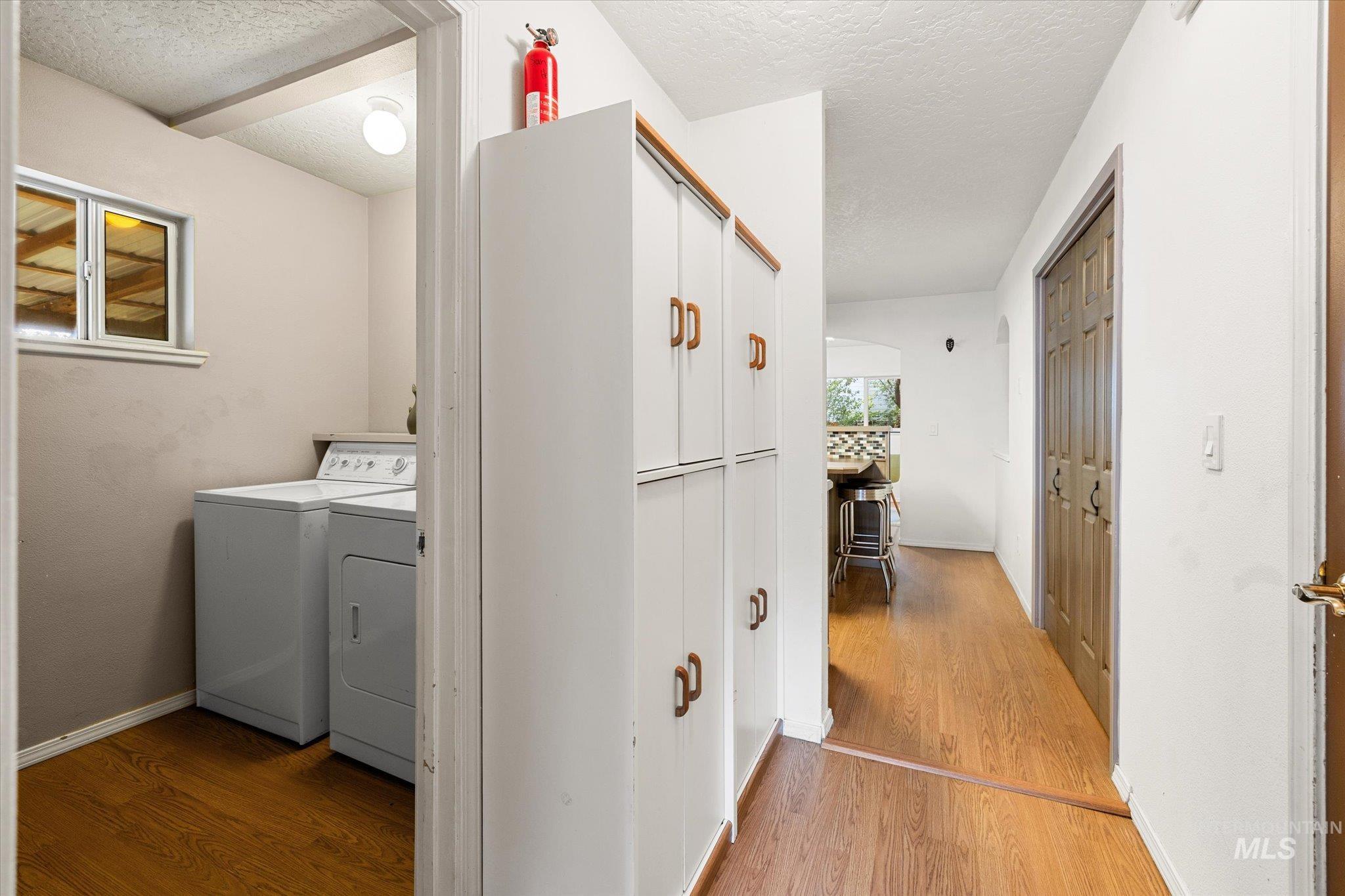 Washroom featuring light wood-style floors, a textured ceiling, and washer and clothes dryer