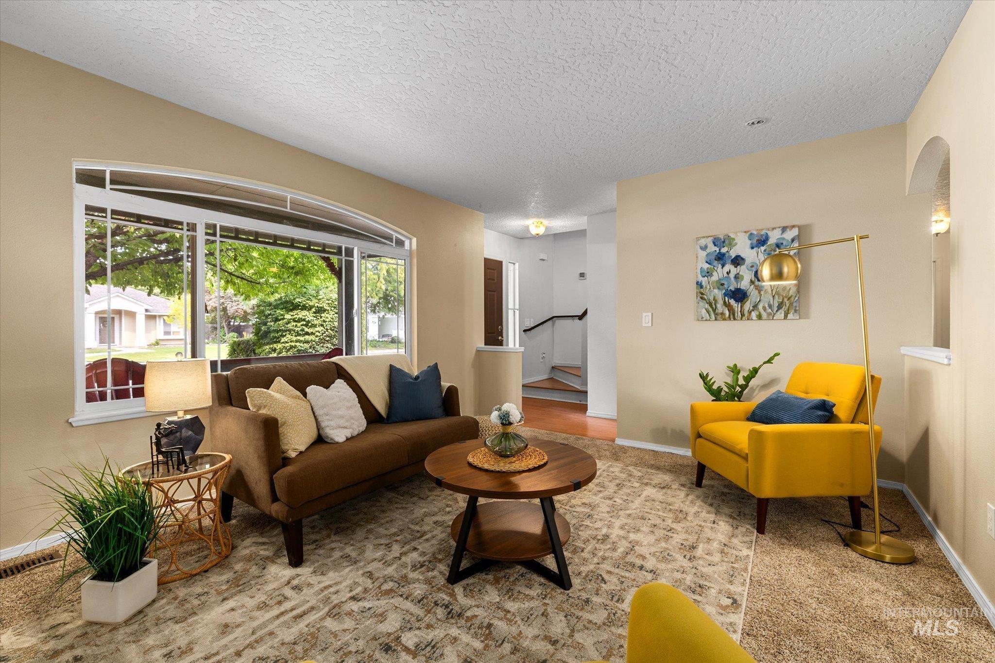 Carpeted living room with a textured ceiling and baseboards