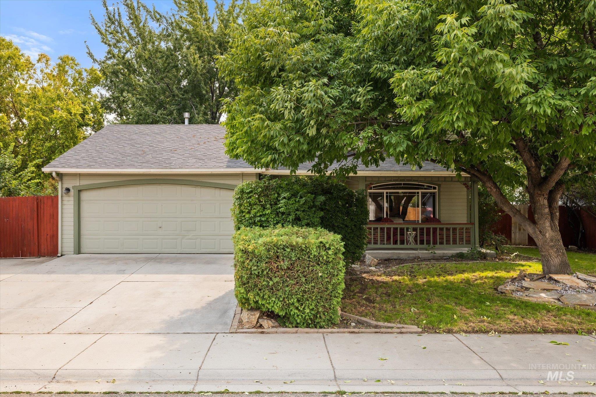 Obstructed view of property with a garage, concrete driveway, roof with shingles, and covered porch