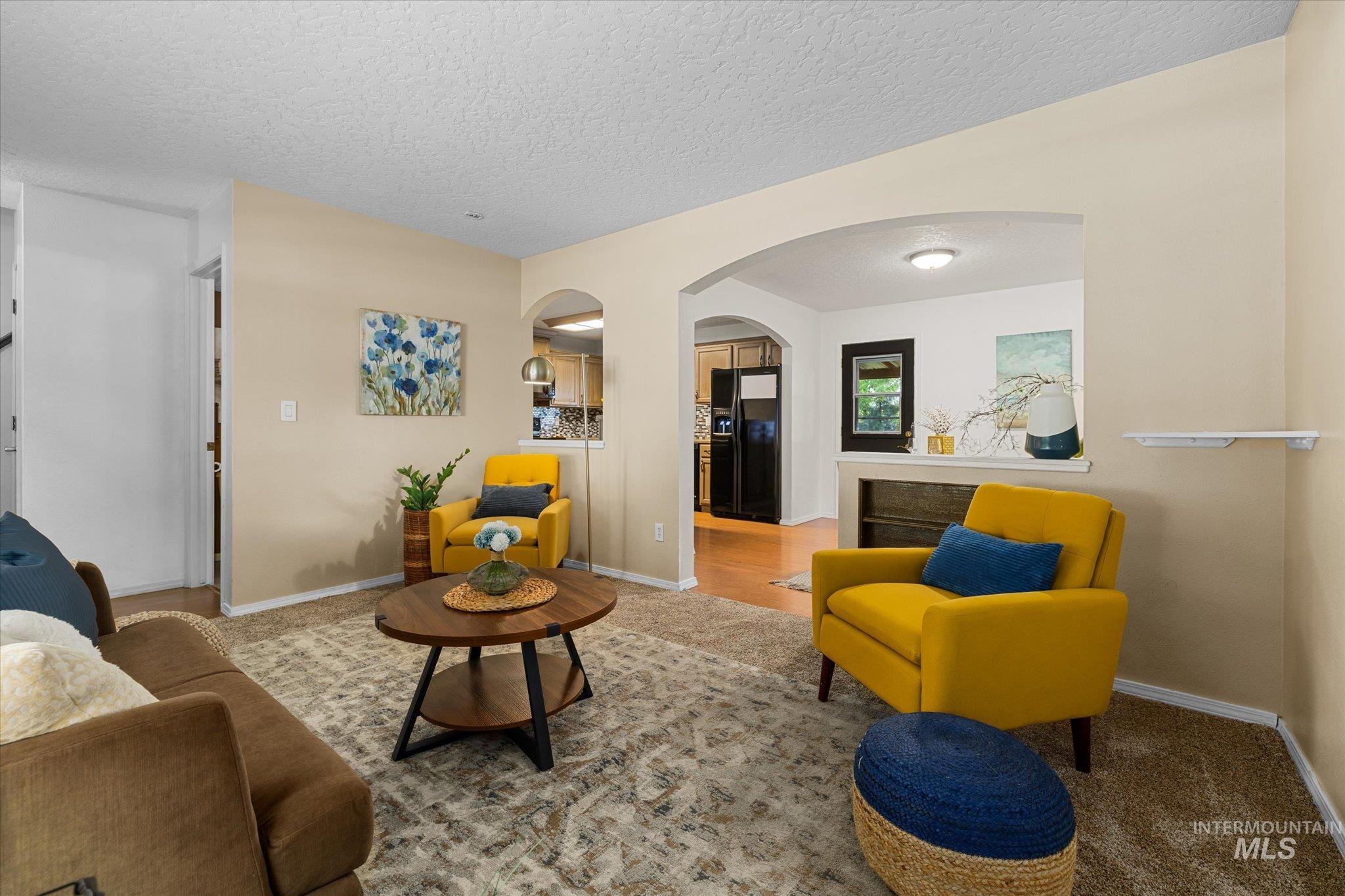 Carpeted living room featuring arched walkways and a textured ceiling